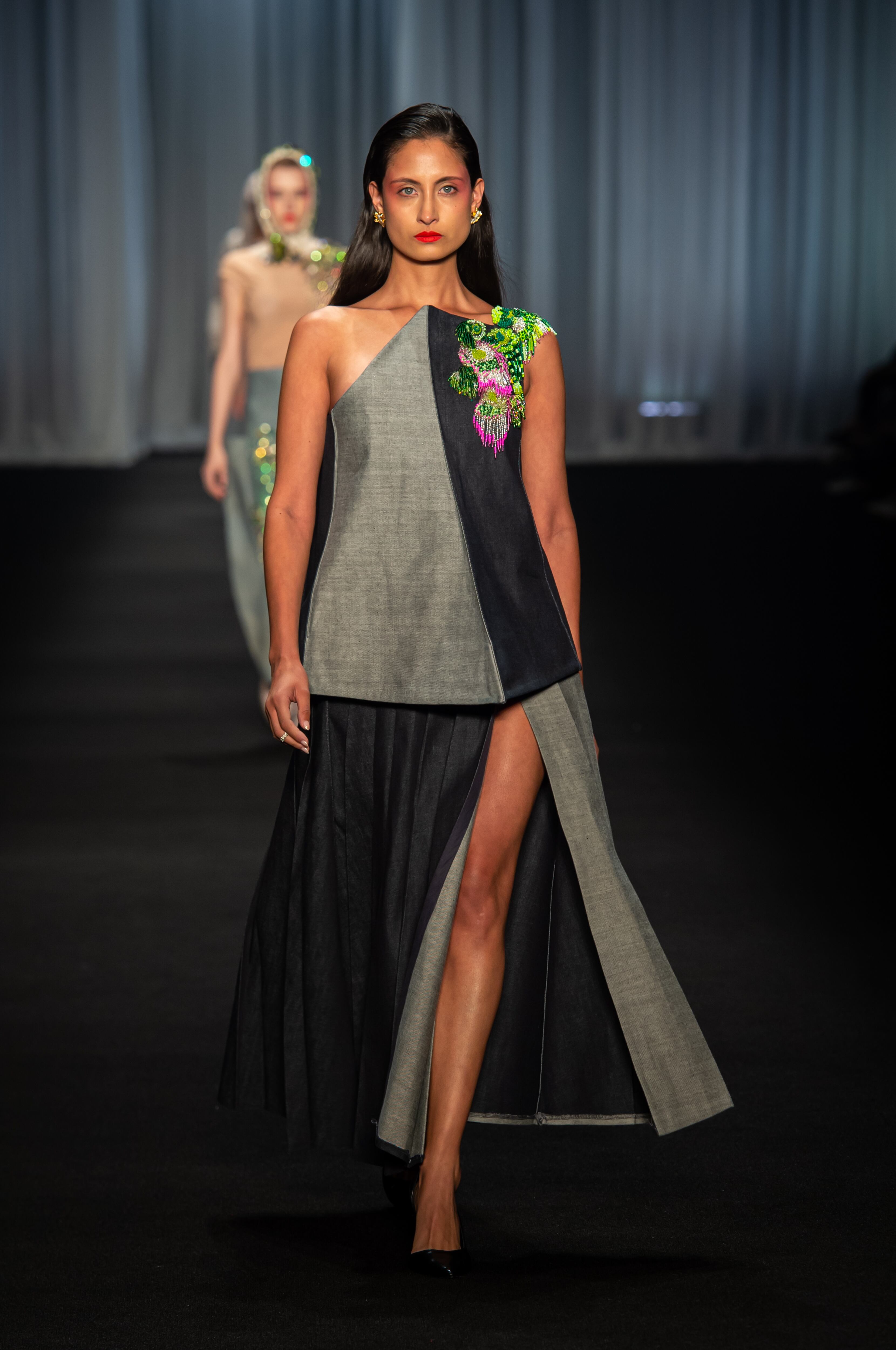 Modelo luciendo un look sofisticado y moderno del Istituto Marangoni sobre la pasarela.