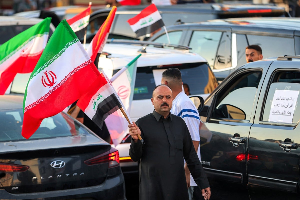 Un hombre sostiene una bandera iraní mientras se desplaza entre vehículos durante las celebraciones por el alto el fuego de dos semanas entre Estados Unidos e Irán en la plaza Tahrir de Bagdad, el 8 de abril de 2026