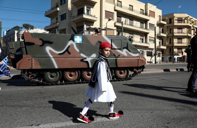 25 de marzo - Un niño vestido con un traje tradicional camina frente a un vehículo militar antes de un desfile en Atenas. El desfile conmemora el Día de la Independencia griega del dominio otomano. FOTO: Yorgos Karahalis/AP