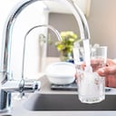 Cerca de la mano de una mujer llenando un vaso de agua directamente del grifo. Captura digital de alta resolución de 42Mp en interiores tomada con lente SONY A7rII y Zeiss Batis 25mm F2.0
