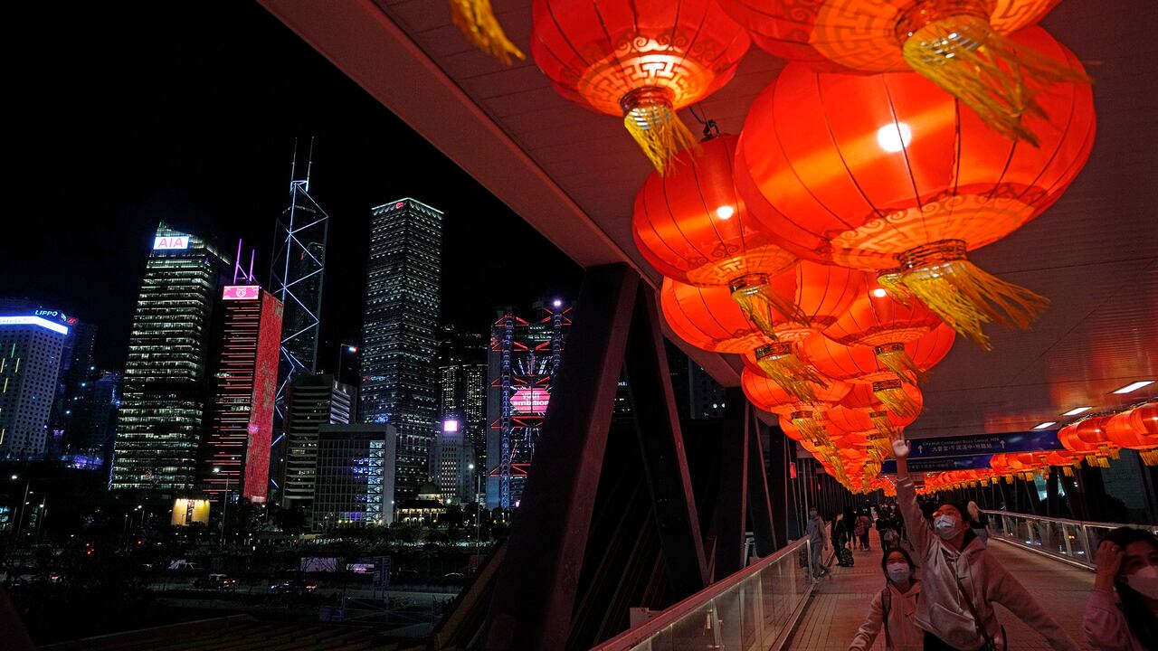 Personas caminan frente a las decoraciones de faroles rojos en un puente antes de las celebraciones del Año Nuevo Lunar en Hong Kong, el domingo 30 de enero de 2022. Foto AP/Kin Cheung