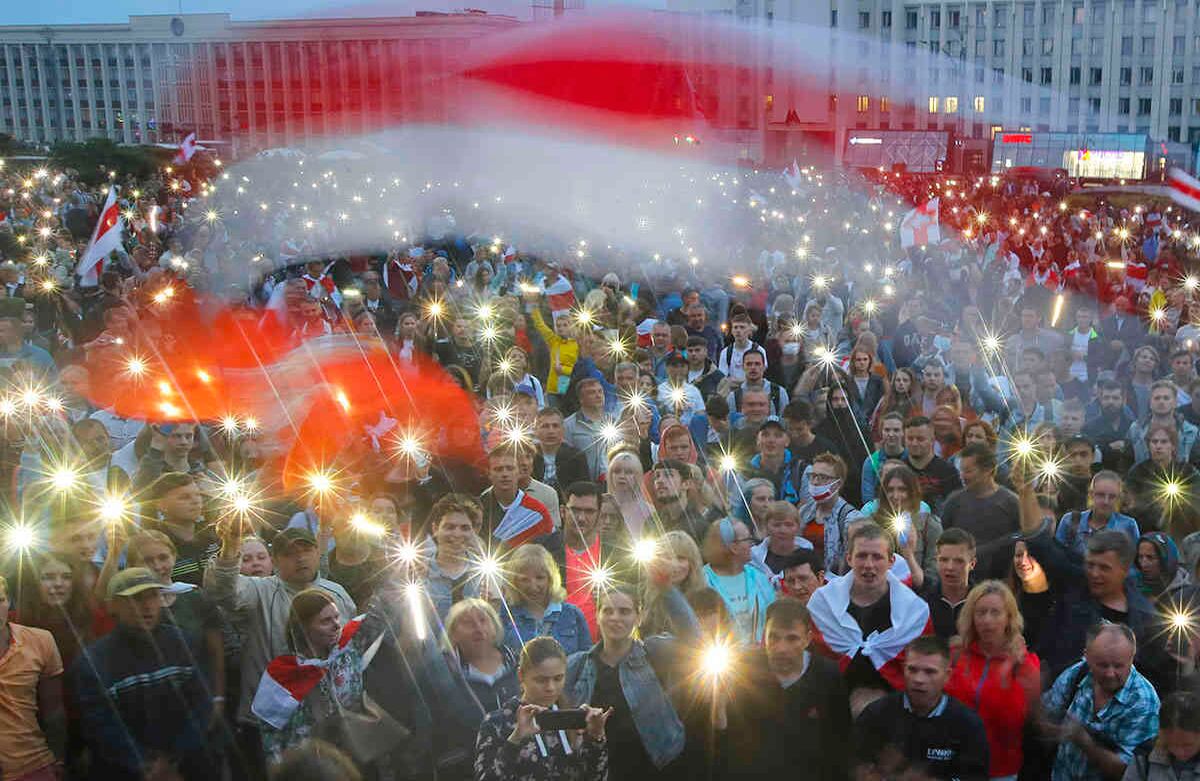 Partidarios de la oposición bielorrusa encienden las luces de sus teléfonos y ondean una vieja bandera nacional bielorrusa durante una manifestación de protesta frente al edificio del gobierno en la Plaza Independiente en Minsk, Bielorrusia, el 19 de agosto de 2020. El líder autoritario de Bielorrusia se quejó por el aliento que desde el extranjero ha alimentado las protestas diarias que exigían su renuncia. Los líderes de la Unión Europea celebraron el miércoles una cumbre de emergencia sobre las controvertidas elecciones presidenciales del país y la feroz represión de los manifestantes. Foto: Dmitri Lovetsky / AP 