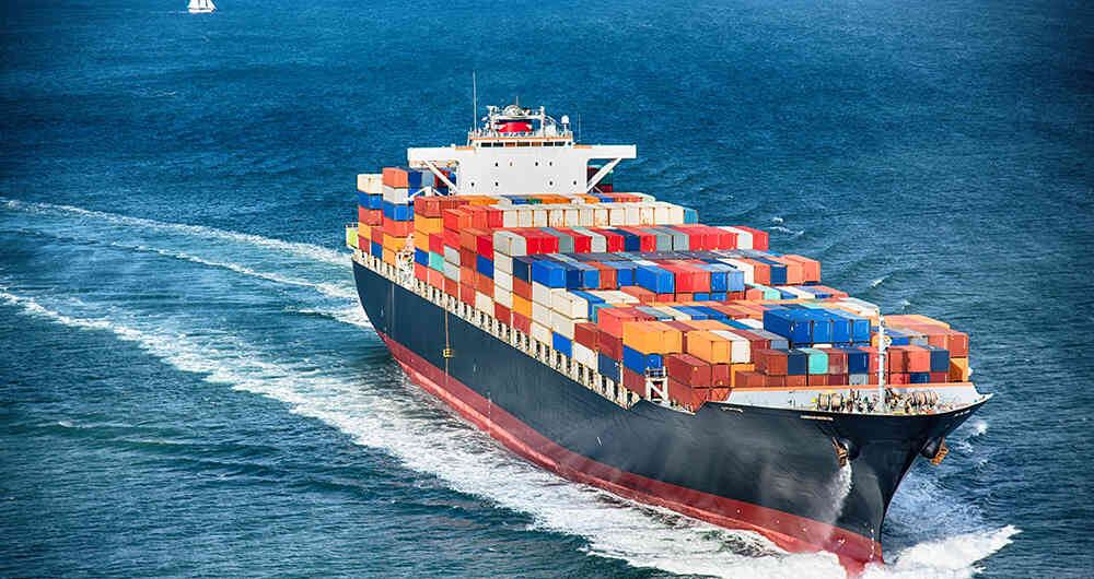 Un barco lleno de contenedores llegando a un puerto.