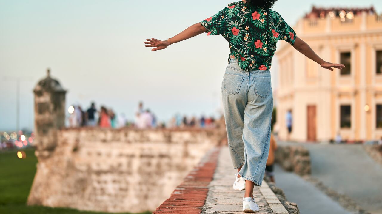 Mujer caminando sobre un muro vista desde atrás en Cartagena