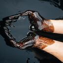 Las manos de aceite caucásicas están dobladas en un tazón de aceite. Derrame de petróleo. Contaminación ambiental. un desastre ambiental. Copie el espacio. foto de alta calidad