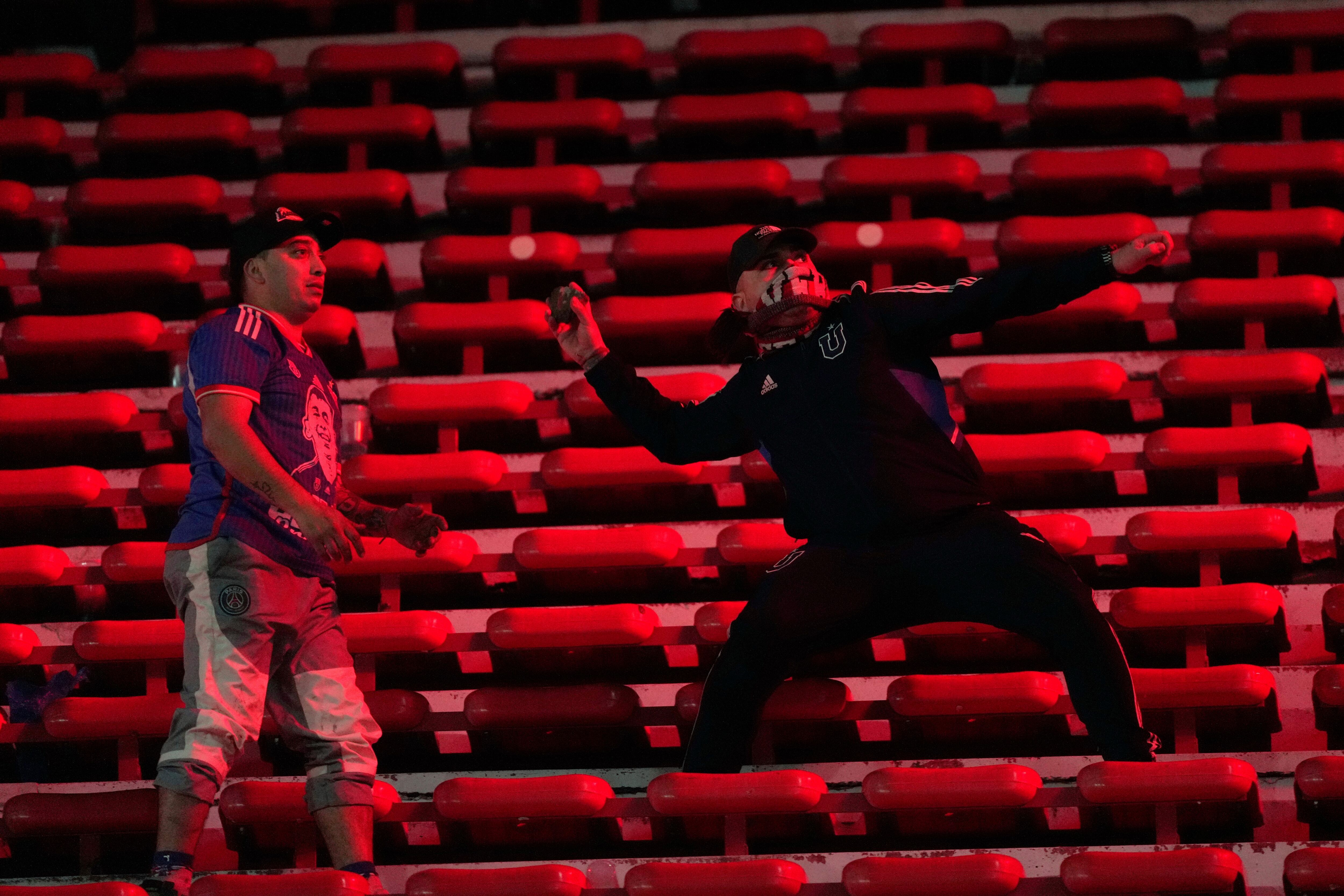 Fans of Universidad de Chile throw stones during a Copa Sudamericana round of sixteen second leg soccer match against Argentina's Independiente at the Libertadores de America stadium in Avellaneda, Argentina, Wednesday, Aug. 20, 2025. (AP Photo/Gustavo Garello)