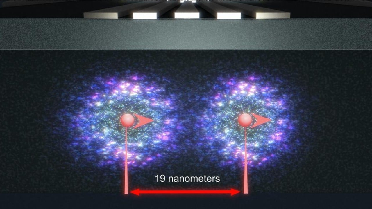 Impresión artística de dos núcleos de fósforo (rojo) y sus electrones enlazados (nubes azules brillantes) dentro del dispositivo cuántico de silicio, separados por 19 nanómetros.