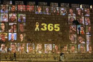 A yellow ribbon along with the number 365, signifying the number of days since the October 7, 2023 attacks carried out by Palestinian militants from the Gaza Strip, is projected along with pictures of the victims of the attacks along the old city walls of Jerusalem late on October 6, 2024 on the eve of the first anniversary of the war that began with the attacks. (Photo by Ahmad GHARABLI / AFP)