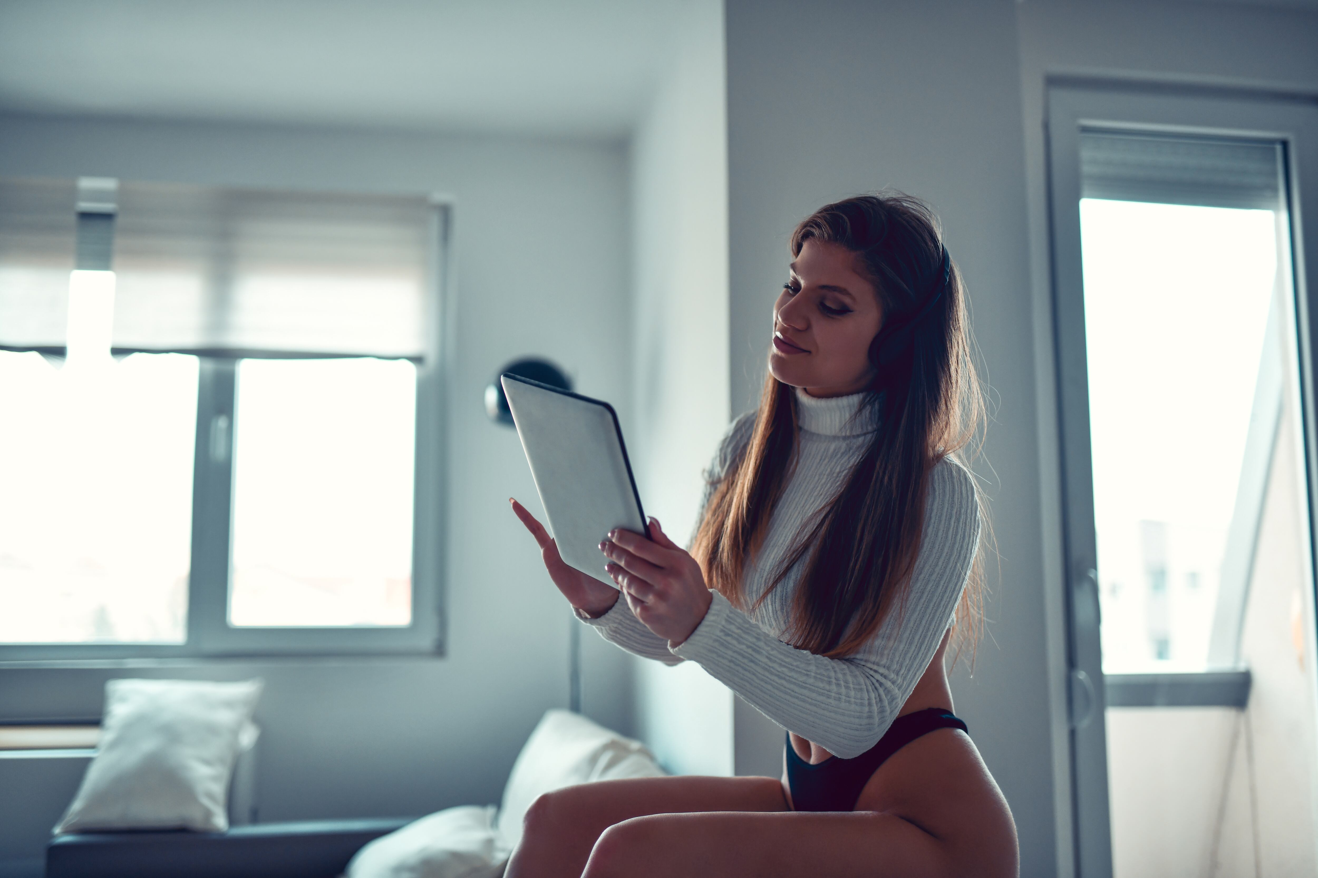 Hermosa mujer en ropa interior con tableta digital para videoconferencia Onlyfans.