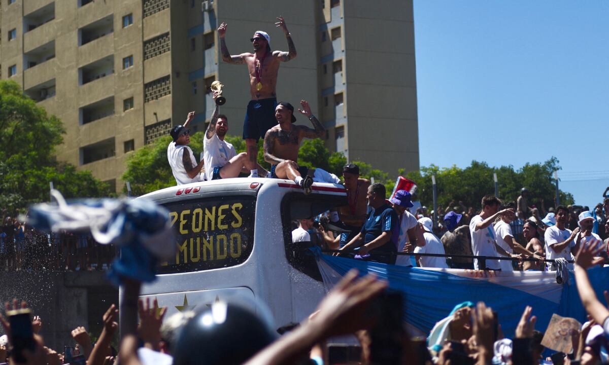 Soccer Football - FIFA World Cup Qatar 2022 - Argentina Victory Parade after winning the World Cup - Buenos Aires, Argentina - December 20, 2022 Argentina's Lionel Messi, Angel Di Maria, Rodrigo De Paul and Leandro Paredes celebrate with teammates on the bus with the World Cup trophy during the victory parade REUTERS/Martin Villar