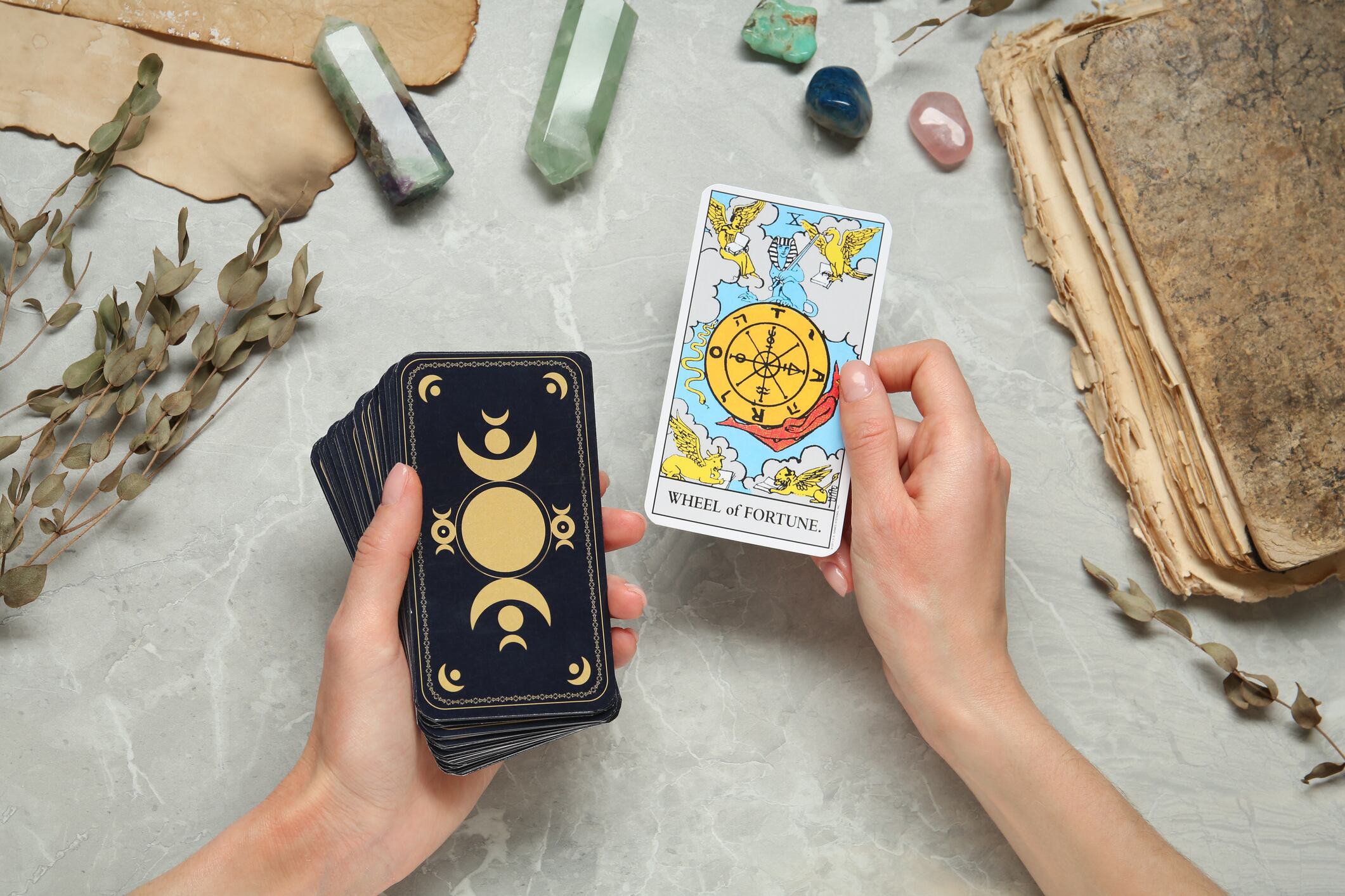Mujer con cartas del tarot en mesa gris.