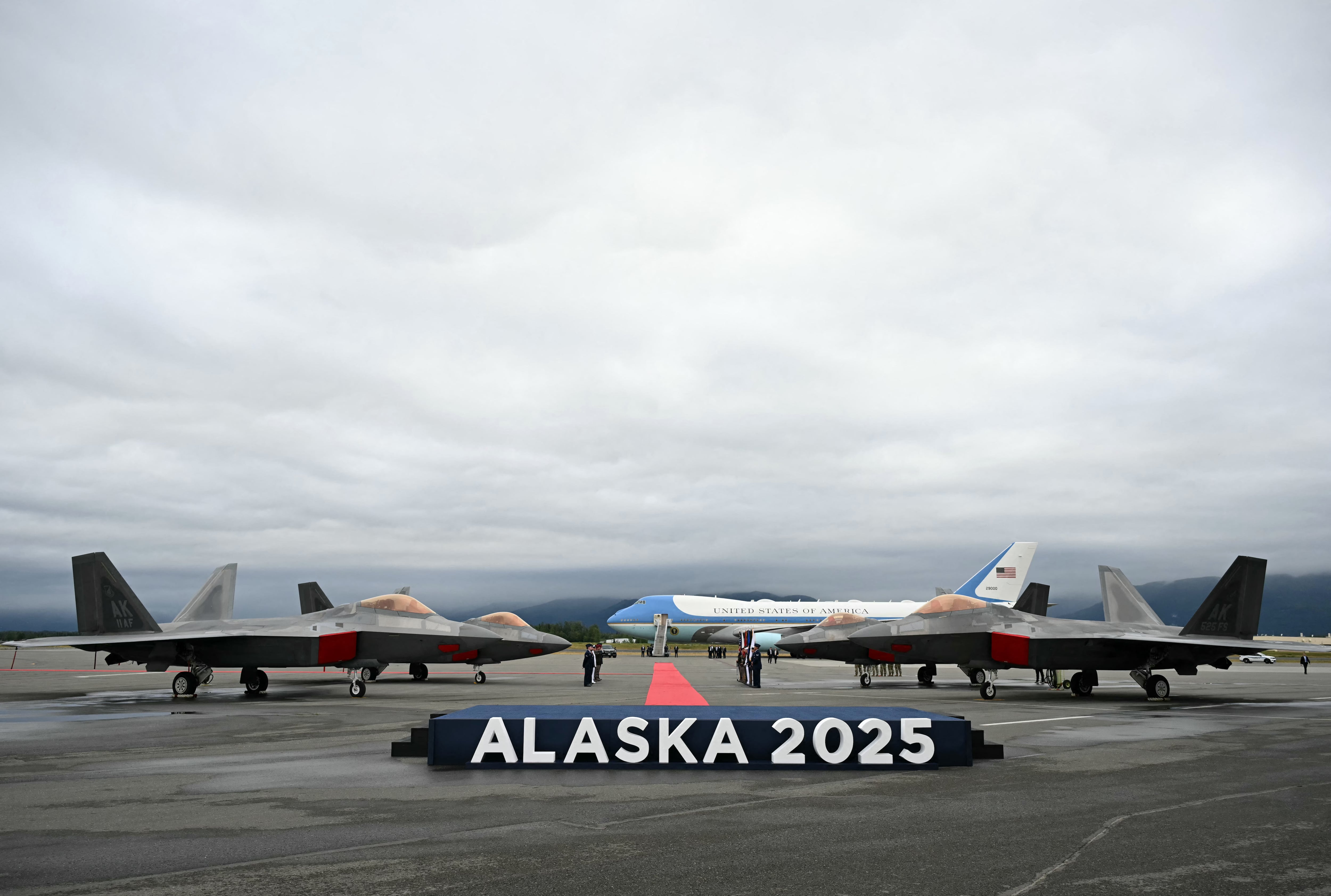 Se ven aviones de combate F-22 en la pista con el Air Force One en la distancia después de que el presidente estadounidense Donald Trump aterrizara en la base conjunta Elmendorf-Richardson en Anchorage, Alaska, el 15 de agosto de 2025. El presidente estadounidense Donald Trump aterrizó en la base militar de Alaska para una cumbre muy esperada con su homólogo ruso Vladimir Putin para presionar para que se ponga fin a la sangrienta guerra de Moscú en Ucrania