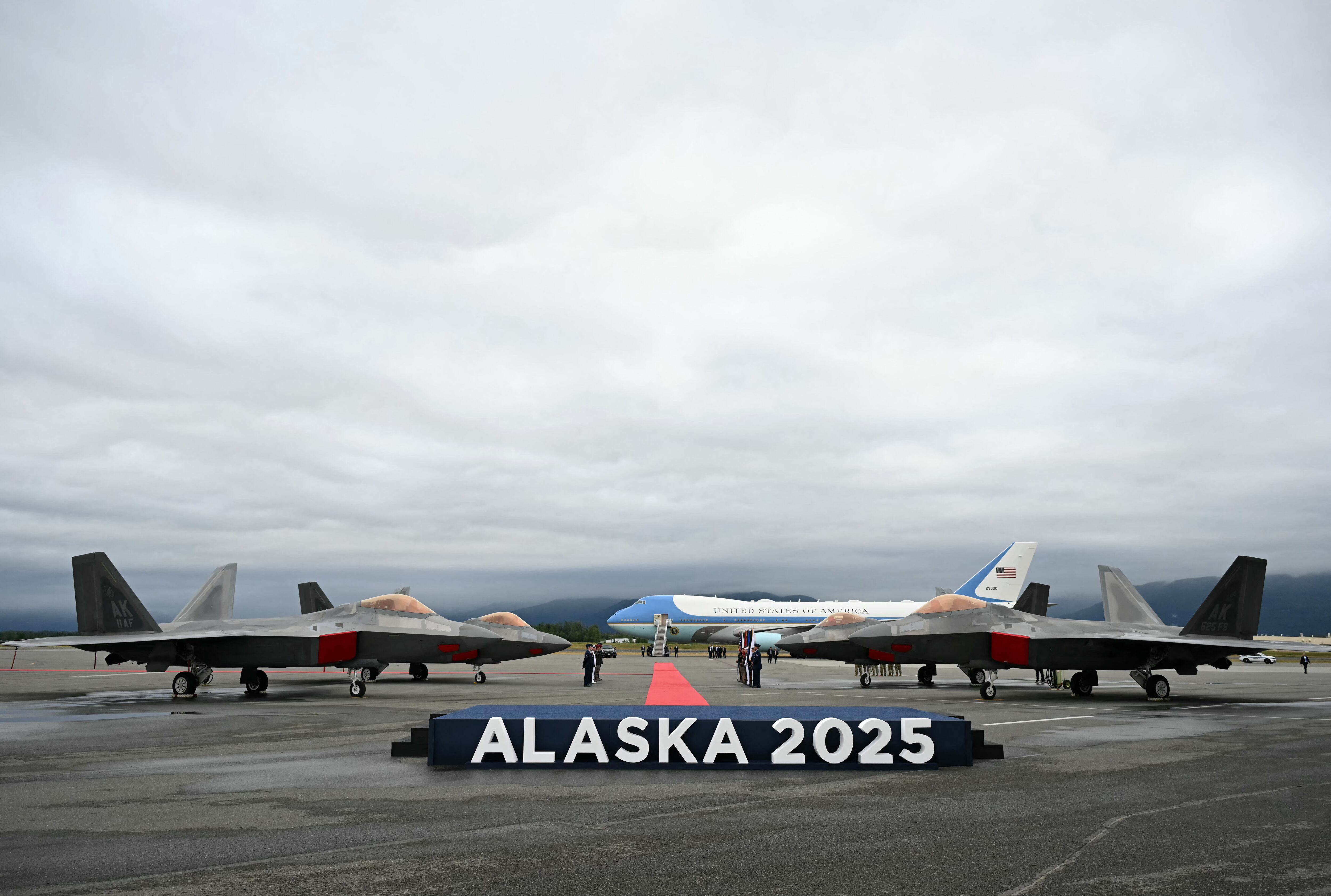 Se ven aviones de combate F-22 en la pista con el Air Force One en la distancia después de que el presidente estadounidense Donald Trump aterrizara en la base conjunta Elmendorf-Richardson en Anchorage, Alaska, el 15 de agosto de 2025. El presidente estadounidense Donald Trump aterrizó en la base militar de Alaska para una cumbre muy esperada con su homólogo ruso Vladimir Putin para presionar para que se ponga fin a la sangrienta guerra de Moscú en Ucrania