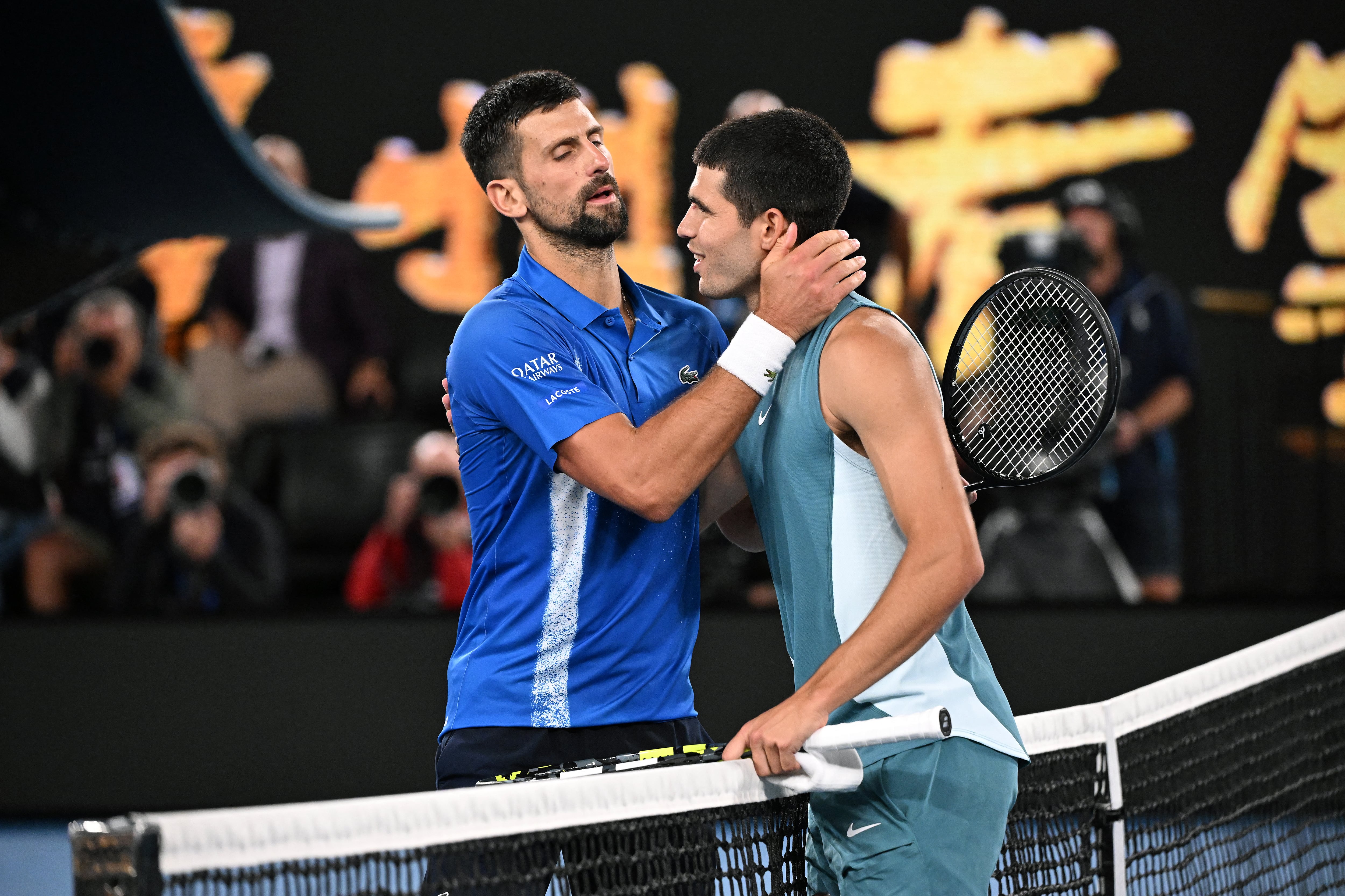El serbio Novak Djokovic (izq.) abraza al español Carlos Alcaraz tras su partido de cuartos de final de individuales masculinos en la décima jornada del Abierto de Australia de tenis en Melbourne el 22 de enero de 2025.