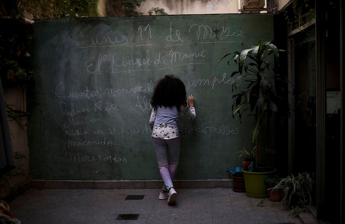 Odara Luna Farmetano utiliza una pared en su casa como pizarra, durante el bloqueo ordenado por el Gobierno con el fin de frenar la propagación del covid-19, en Buenos Aires, Argentina, el 11 de mayo. El país latinoamericano registra 7.121 casos de contagio. Foto: Natacha Pisarenko/ AP. 