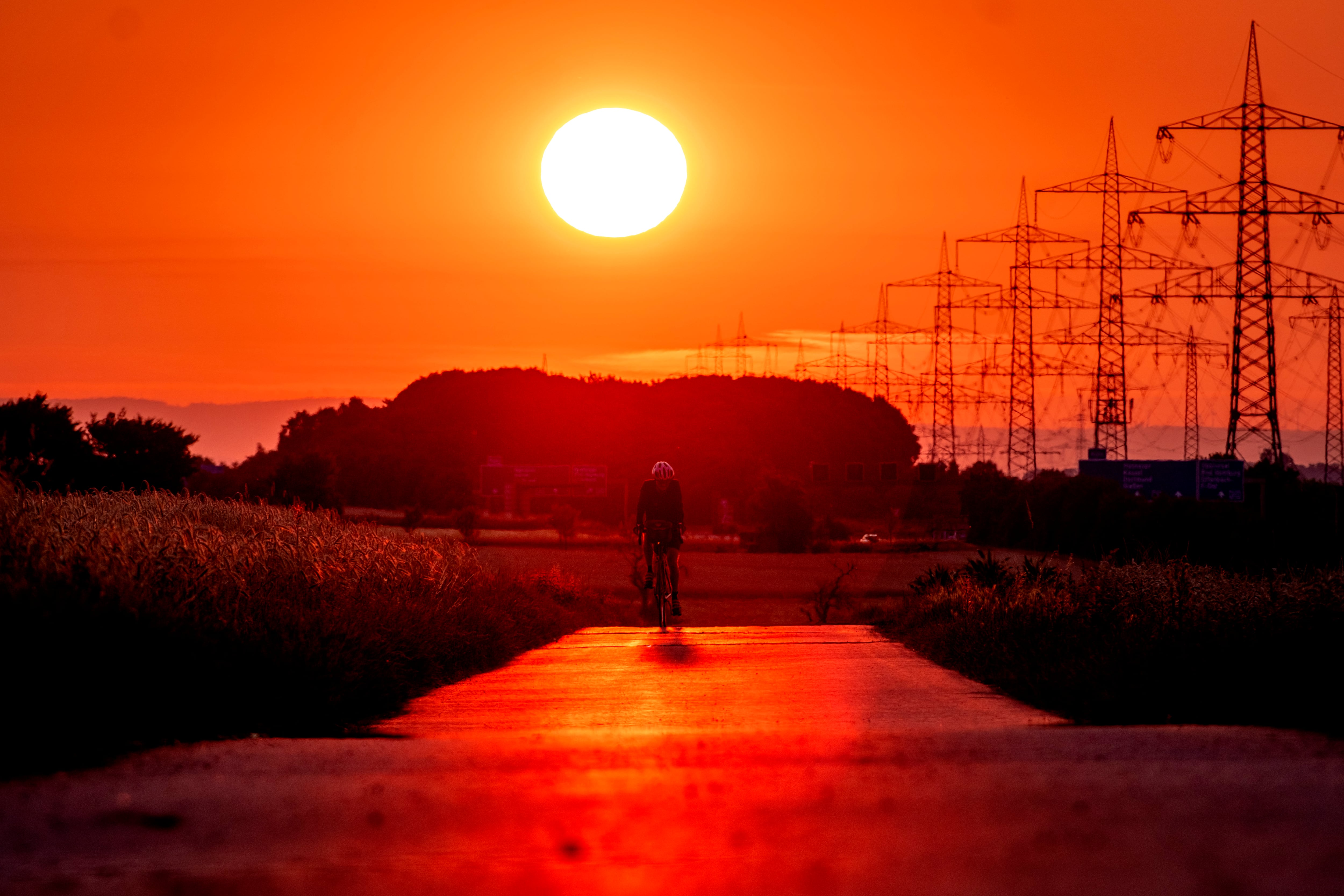 Un hombre monta su bicicleta en una pequeña carretera en las afueras de Frankfurt, Alemania, mientras sale el sol el 9 de julio de 2023. Los científicos dicen que las temperaturas aplastantes que cubrieron Europa el verano pasado pueden haber provocado más de 61,000 muertes