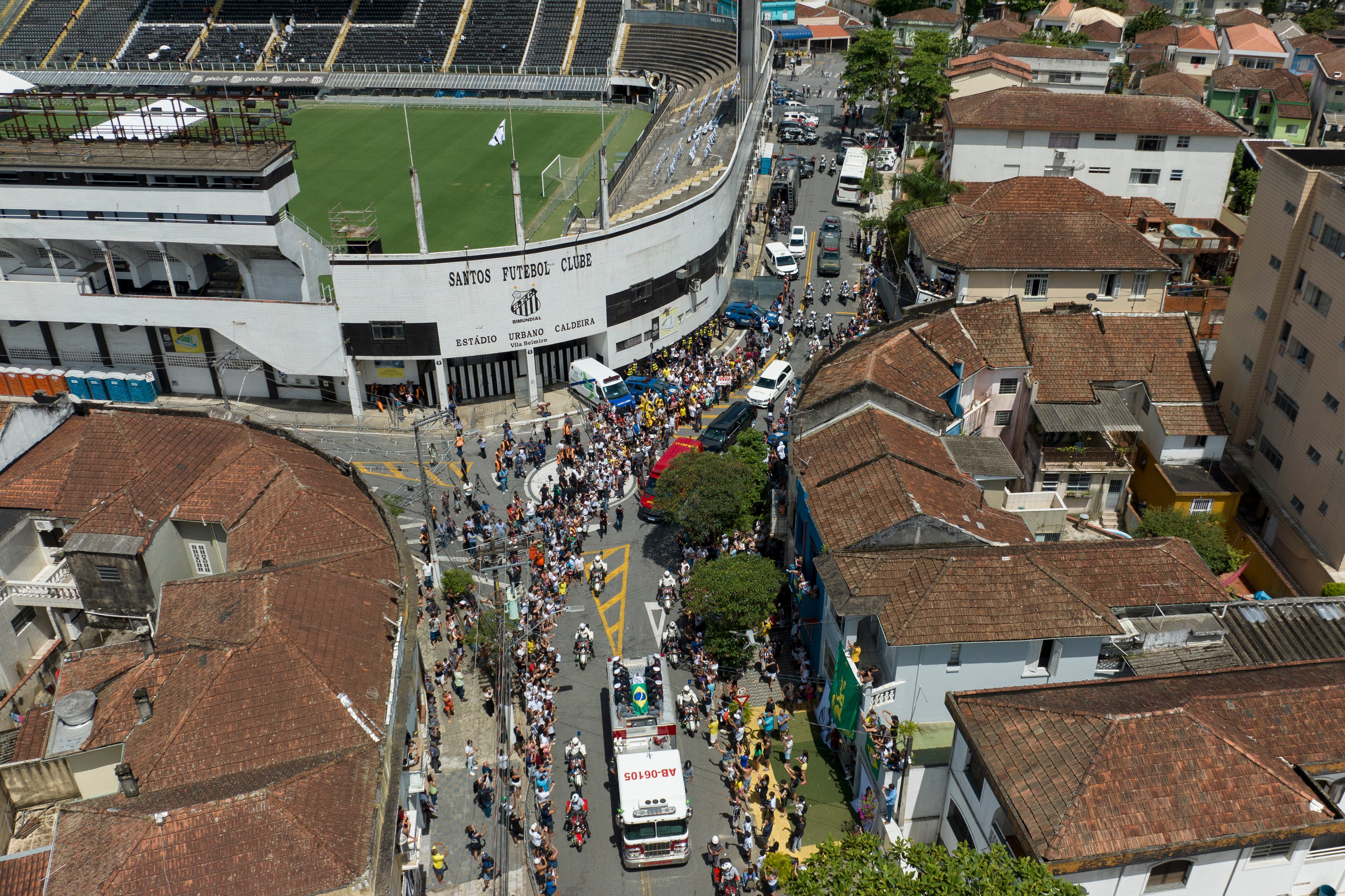 The casket of late Brazilian soccer great Pele is draped in the Brazilian and Santos FC soccer club flags as his remains are transported from Vila Belmiro stadium, where he laid in state, to the cemetery during his funeral procession in Santos, Brazil, Tuesday, Jan. 3, 2023. (AP Photo/Andre Penner)