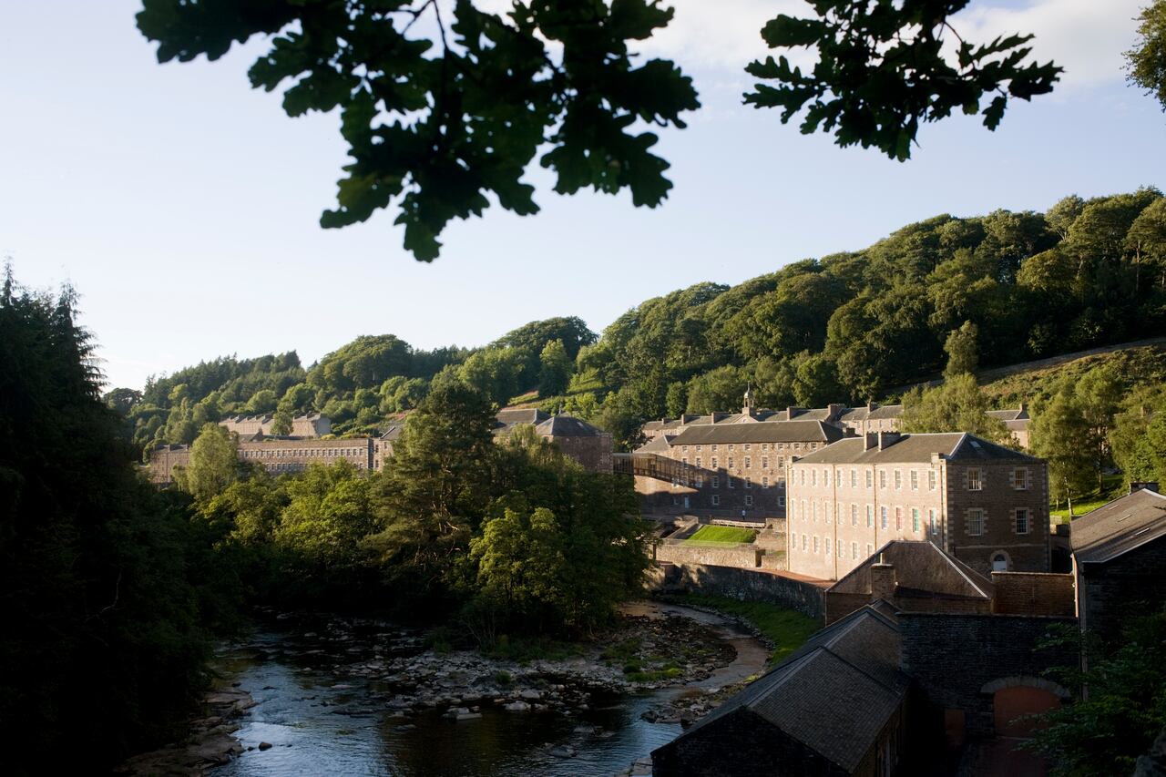New Lanark, the Scottish industrial revolution community village managed by social pioneer Robert Owen. New Lanark is on the River Clyde, approximately 1.4 miles (2.2 kilometres) from Lanark, in South Lanarkshire, Scotland. It was founded in 1786 by David Dale, who built cotton mills and housing for the mill workers. Dale built the mills there to take advantage of the water power provided by the river. Under the ownership of a partnership that included Dale's son-in-law, Robert Owen, a Welsh philanthropist and social reformer, New Lanark became a successful business and an epitome of utopian socialism. The New Lanark mills operated until 1968 and is now one of five UNESCO World Heritage Sites in Scotland. | Location: New Lanark, Scotland, UK.