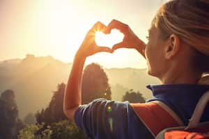 Mujer joven de senderismo en el parque forestal nacional de Zhangjiajie, hace un marco de dedo en forma de corazón. Me encanta el concepto de compartir la pasión por los viajes de la naturaleza.