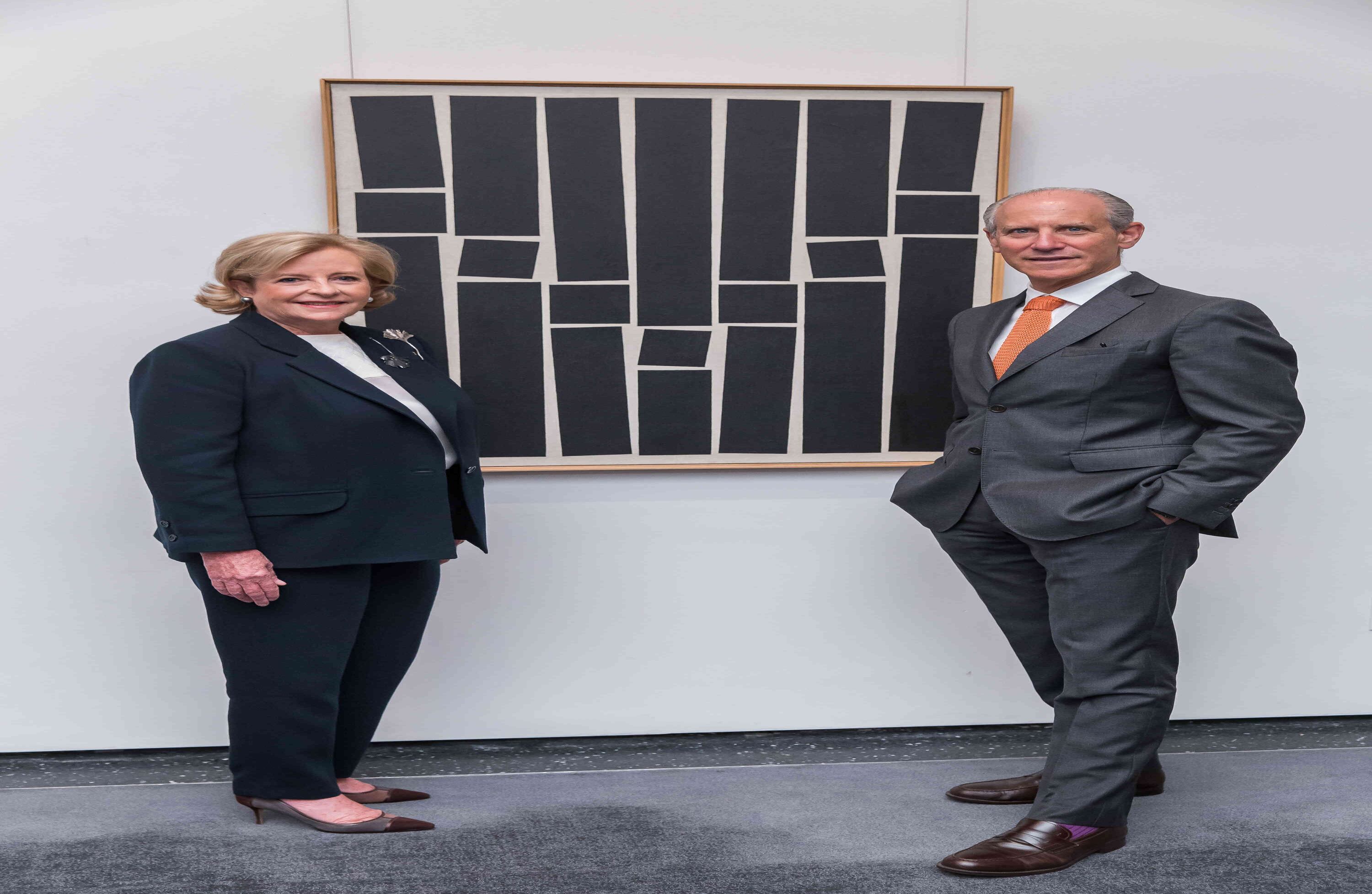 B. Patricia Phelps de Cisneros and Glenn D. Lowry, Director, The Museum of Modern Art, stand next to Hélio Oiticica.