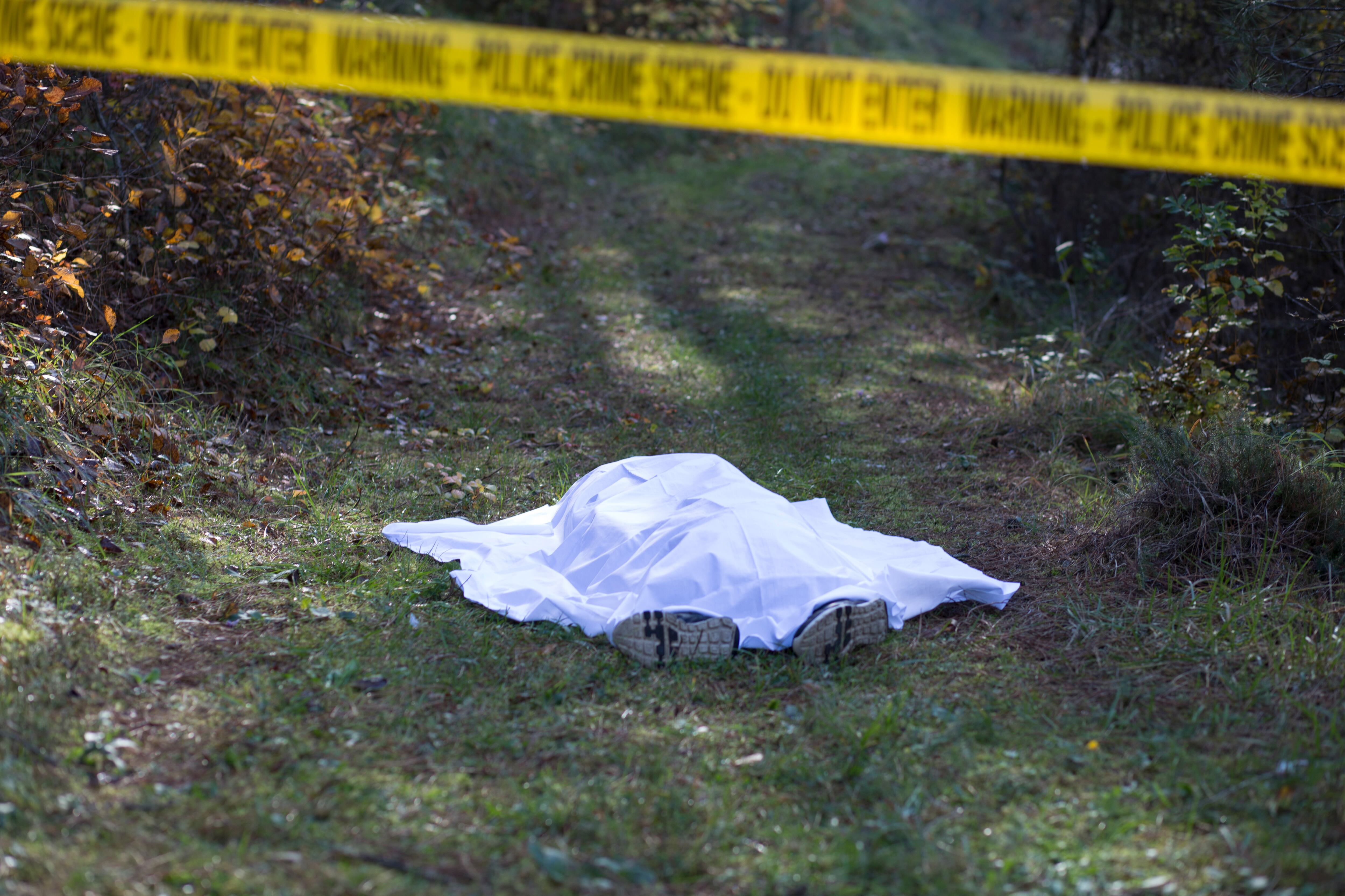 Cadáver, muerto cubierto con una manta blanca y encerrado con la cinta amarilla