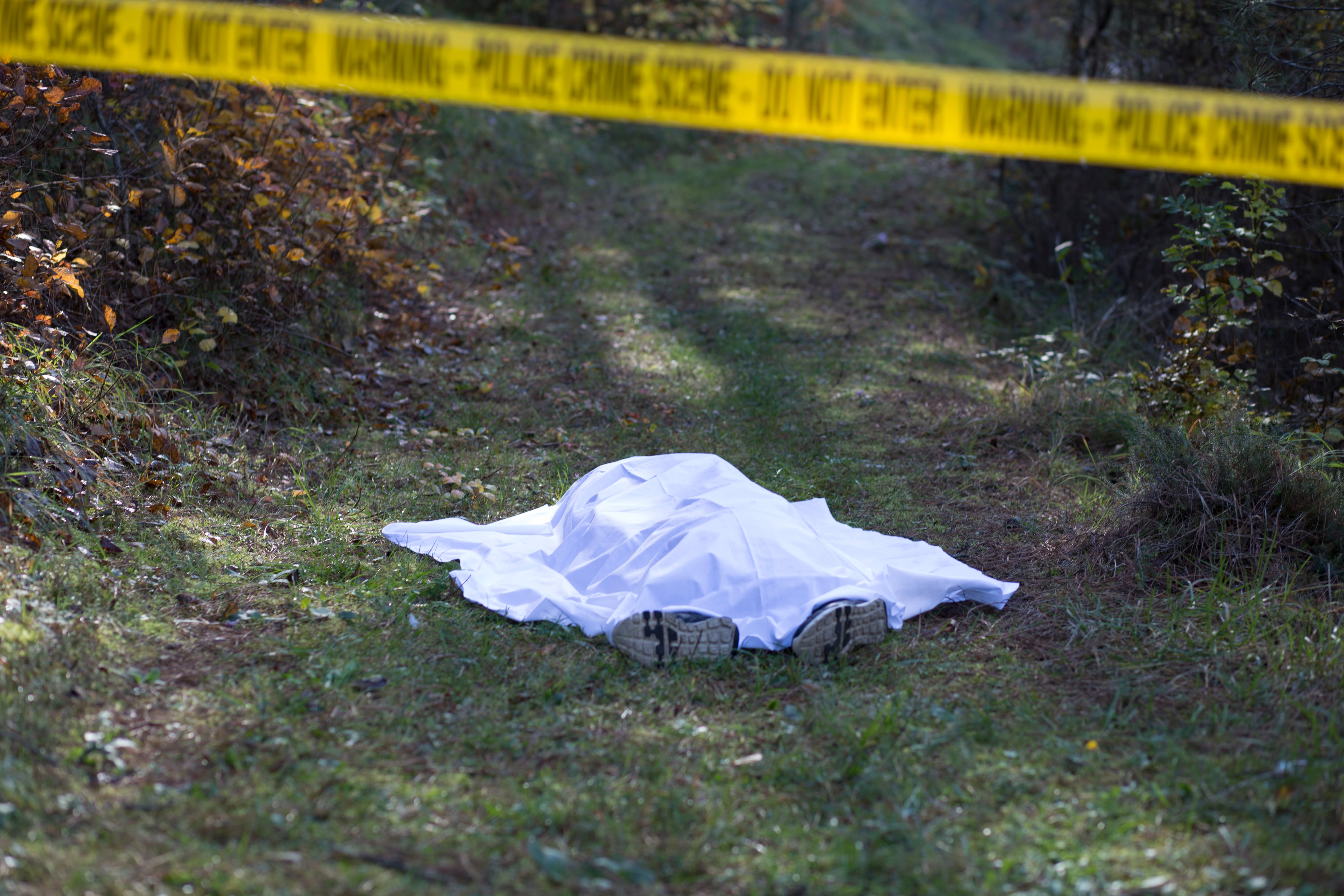 Cadáver, muerto cubierto con una manta blanca y encerrado con la cinta amarilla