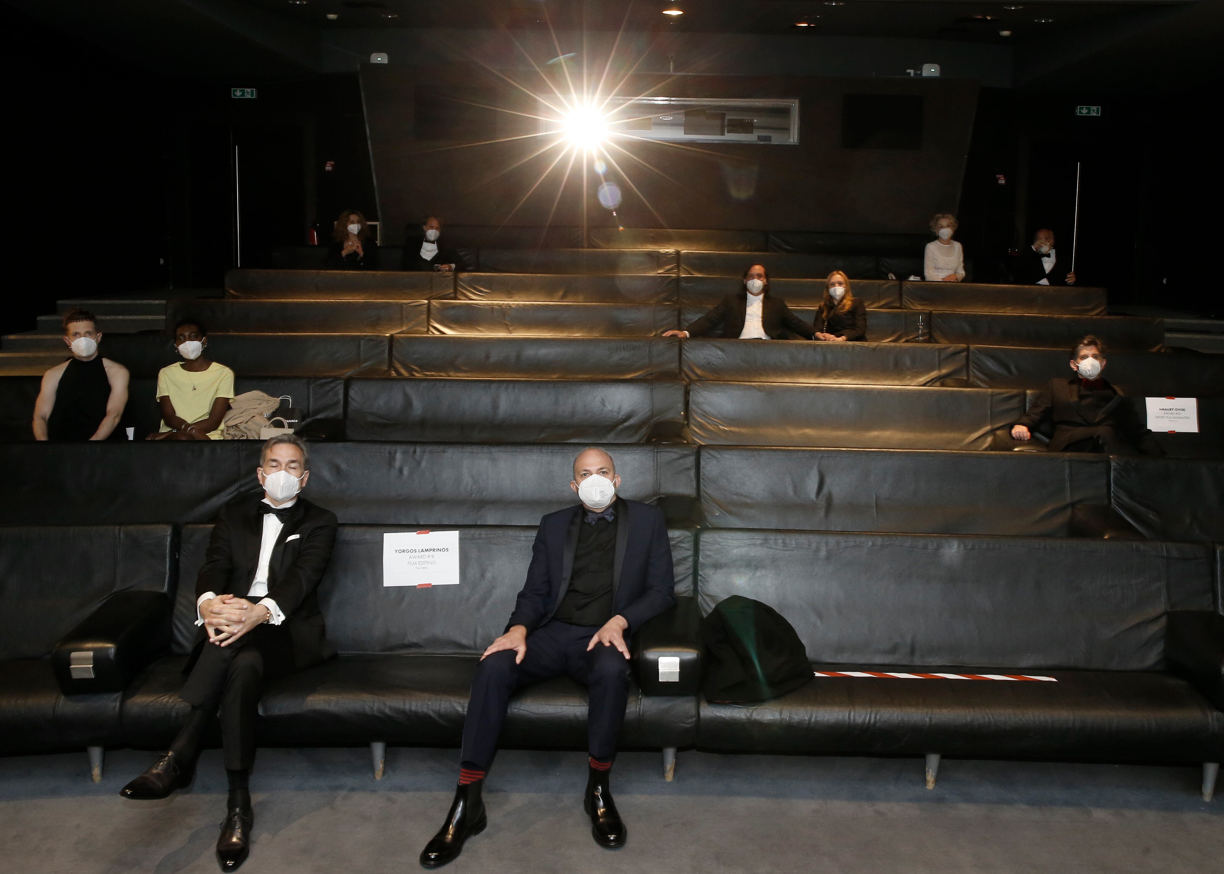Nominees, including: Yorgos Lamprinos, bottom center, Adrien Merigeau, center left, Amaury Ovise, center right, Nicolas Becker, center, Jean-Louis Livi, top right, and Florian Zeller, top second left, attend a screening of the Oscars on Monday April 26, 2021 in Paris, France. (AP Photo/Lewis Joly, Pool)