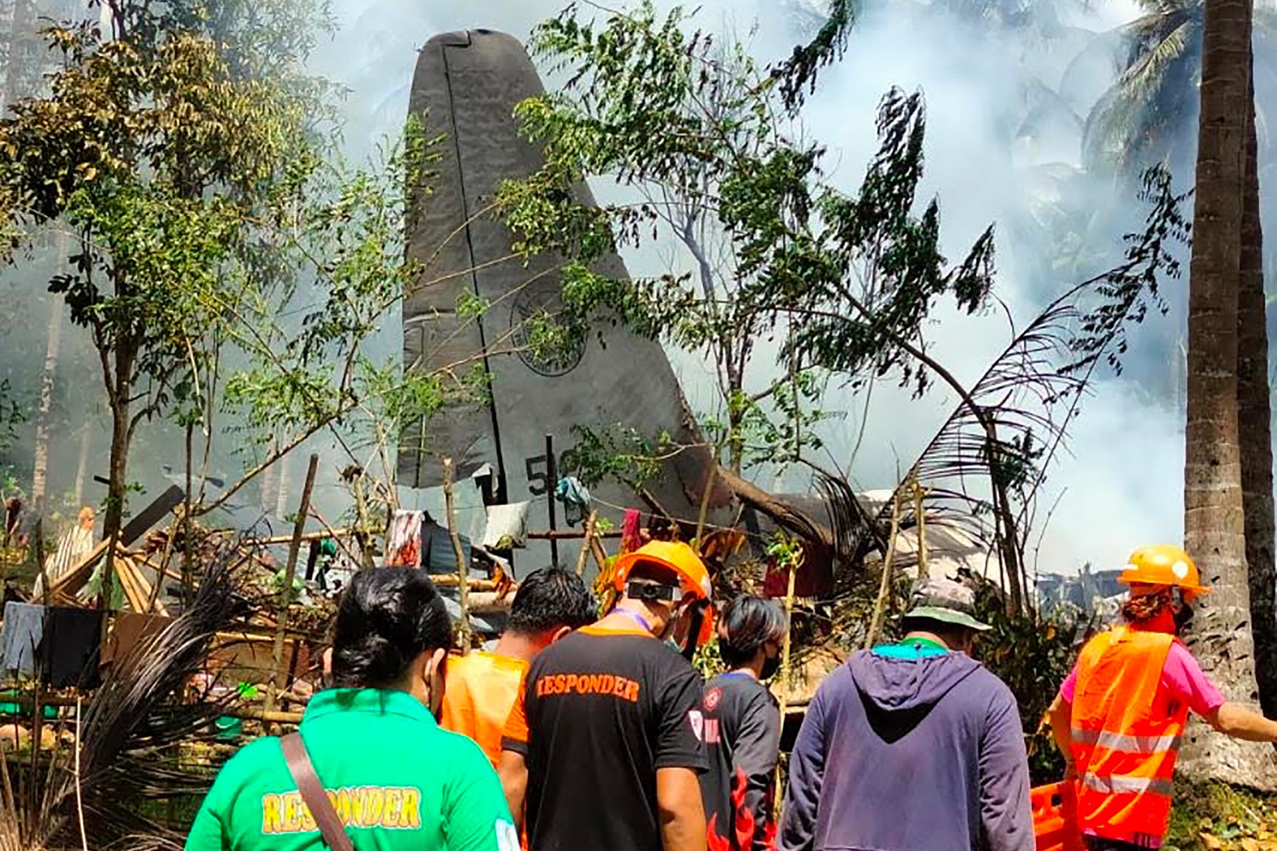 In this handout photo taken on July 4, 2021 and received from the Philippine military Joint Task Force-Sulu (JTF-Sulu), rescue workers arrive as smoke billows from the wreckage of a Philippine Airforce C-130 transport plane after it crashed near the airport in Jolo town, Sulu province on the southern island of Mindanao. (Photo by Handout / Joint Task Force-Sulu / AFP) / -----EDITORS NOTE --- RESTRICTED TO EDITORIAL USE - MANDATORY CREDIT "AFP PHOTO / JOINT TASK FORCE-SULU (JTF-SULU) " - NO MARKETING - NO ADVERTISING CAMPAIGNS - DISTRIBUTED AS A SERVICE TO CLIENTS
