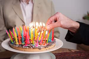 93 colored candles on a cake are being lit.