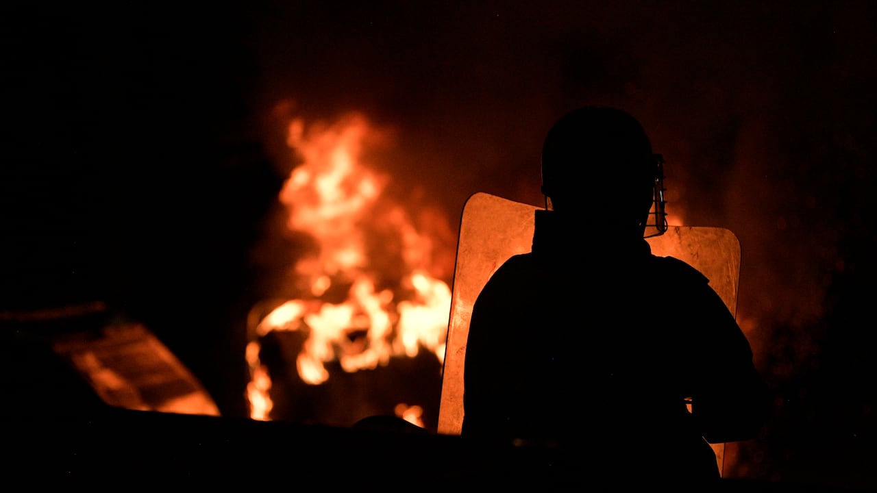 A riot police officer stands in front of a bonfire during a protest against police brutality in Bogota, on September 10, 2020. - At least 10 people were killed and hundreds wounded after rioting broke out in the Colombian capital Bogota during protests over the death of a man repeatedly tasered by police, authorities said Thursday. (Photo by Raul ARBOLEDA / AFP)