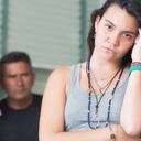 Padres concentrados muy molestos regañando a su hija empresaria usando una laptop en el escritorio de la oficina