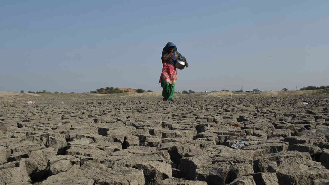 En India el agua se está agotando. Una mujer india camina sobre el lecho seco del lago Chandola en Ahmedabad. Foto: SAM PANTHAKY / AFP