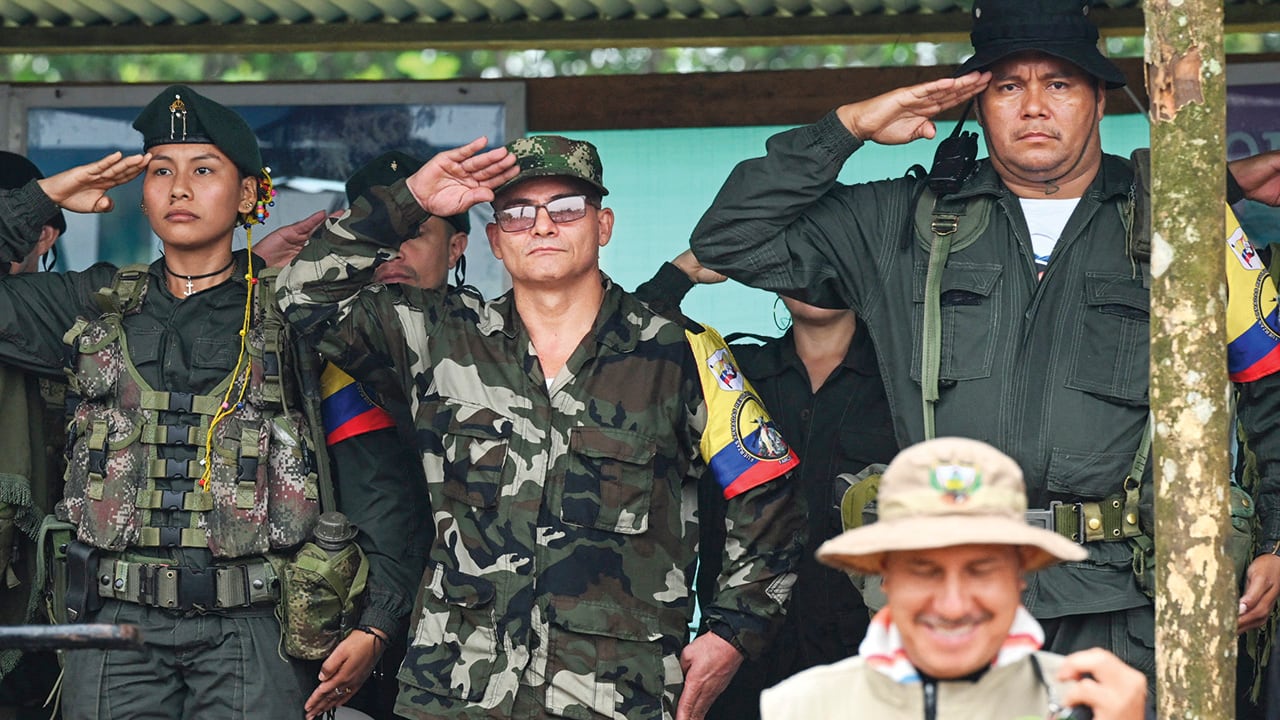 FARC-EP dissidence top commander, aka Ivan Mordisco (C), gives a military salute next to commander Calarca (R) during a meeting with local communities in San Vicente del Caguan, Caqueta department, Colombia, on April 16, 2023. An armed dissident group of Colombia's disbanded FARC guerrillas said Sunday it was "ready" to start peace talks with the government from May 16. "We are announcing to the world that our delegates to the dialogue table with the Colombian government... are ready for May 16," the EMC dissident grouping, which rejected a 2016 peace deal that disarmed the FARC, said through a spokesperson. (Photo by JOAQUIN SARMIENTO / AFP)