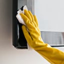 Woman cleaning the TV with damp cloths and wearing yellow gloves during coronavirus, covid 19 quarantine. Maintain hygiene at home, clean dust and bacteria, clean viruses from television.
