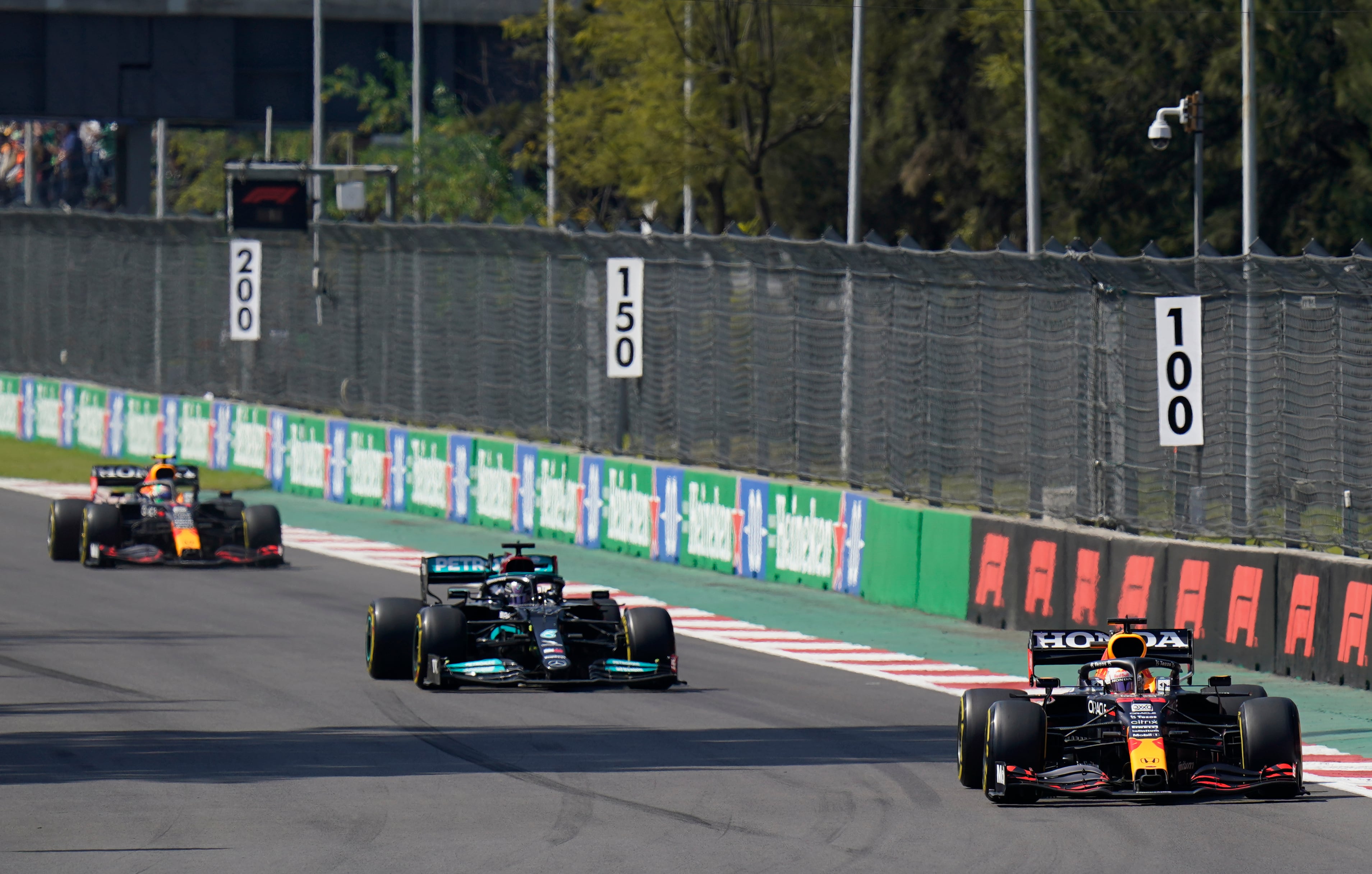 Red Bull driver Max Verstappen, of The Netherlands, leads the race, with Mercedes driver Lewis Hamilton, of Britain, following a close second and Red Bull driver Sergio Perez, of Mexico, third, during the Formula One Mexico Grand Prix auto race at the Hermanos Rodriguez racetrack in Mexico City, Sunday, Nov. 7, 2021. (AP/Eduardo Verdugo)