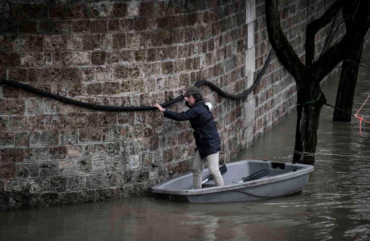 Un hombre usa un bote cuando sale de una casa en el río Seine inundado en París, el 25 de enero de 2018. El Sena siguió en aumento, inundando las calles y colocando a los museos en una situación de emergencia a medida que las precipitaciones récord empujaban a los ríos sobre sus orillas en el noreste de Francia. / AFP PHOTO / Philippe López.
