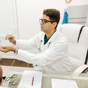 Male doctor examining throat of young female patient in doctor's office