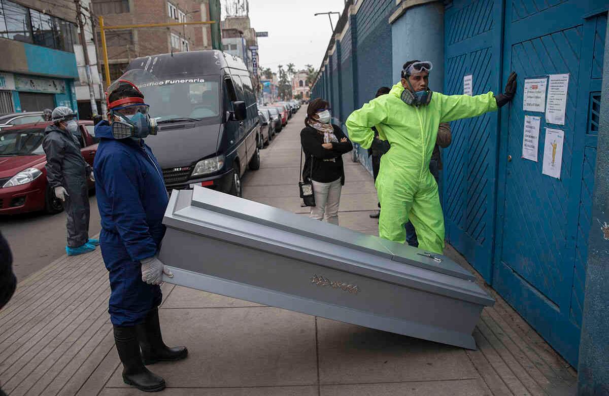 Trabajadores de funerarias esperan su turno para recoger el cuerpo de una persona que murió de covid-19, frente al hospital público de Almenara, en Lima, Perú, el 25 de junio. Foto: Rodrigo Abd / AP