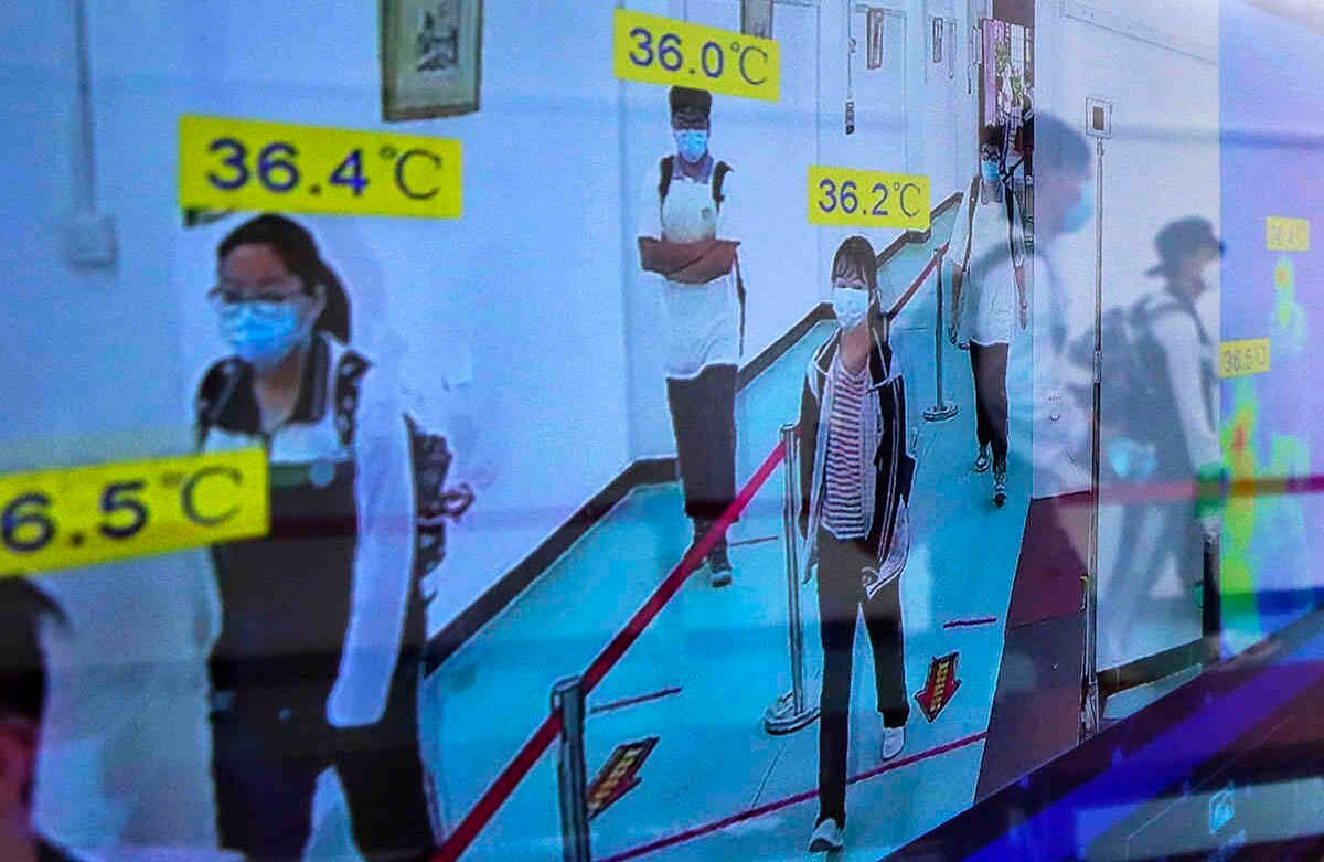 Los estudiantes  se reflejan en la pantalla de un monitor que muestra la temperatura de su cuerpo cuando llegan a una escuela secundaria en Wuhan, en la provincia de Hubei, en el centro de China. Andy Wong / AP