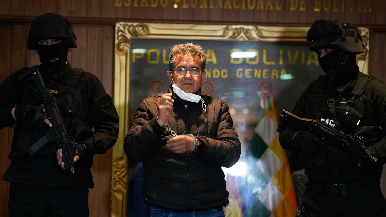 Policías escoltan al excoronel de la policía Maximiliano Dávila (centro) durante su presentación ante los medios de comunicación en la oficina del Comando General de la Policía Boliviana, en La Paz, el domingo 23 de enero de 2022. (AP Foto/Juan Karita)