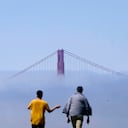 Los peatones caminan sobre una colina frente al puente Golden Gate parcialmente oscurecido por la niebla en San Francisco, el martes 16 de agosto de 2022. Foto AP/Jeff Chiu
