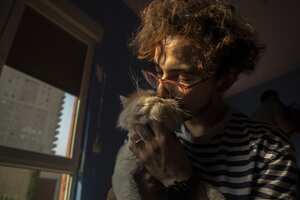 Se ve a un hombre acariciando a un gato en el hotel que ofrece varios servicios como cuidado personal y alojamiento para perros y gatos en Erbil, Irak, el 18 de octubre de 2022. (Foto de Ahsan Mohammed Ahmed/Agencia Anadolu a través de Getty Images)