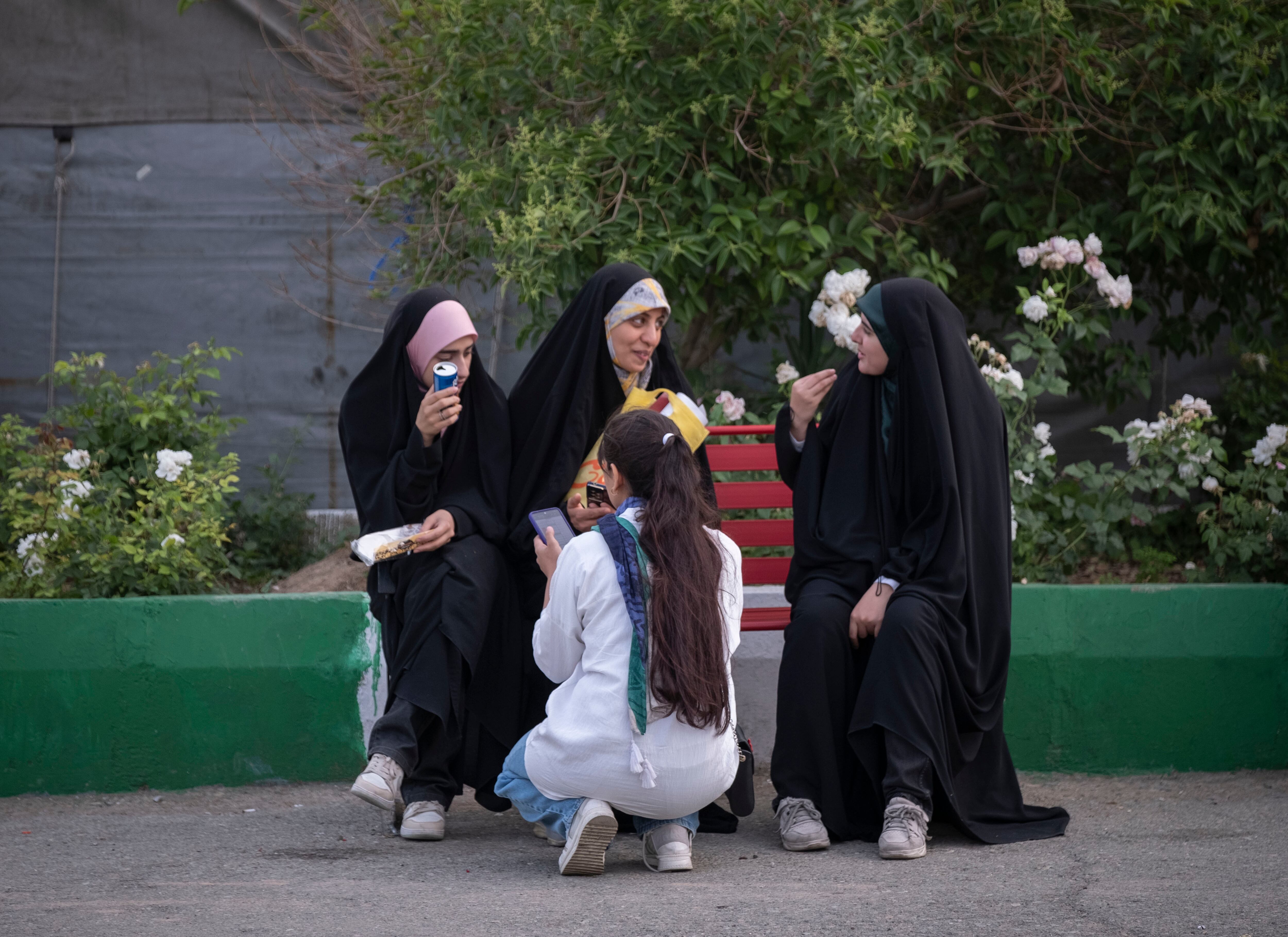 Una joven iraní sin el hiyab obligatorio se sienta junto a sus amigas con velo mientras visita la Feria Internacional del Libro en la gran mezquita Imam Jomeini en el centro de Teherán