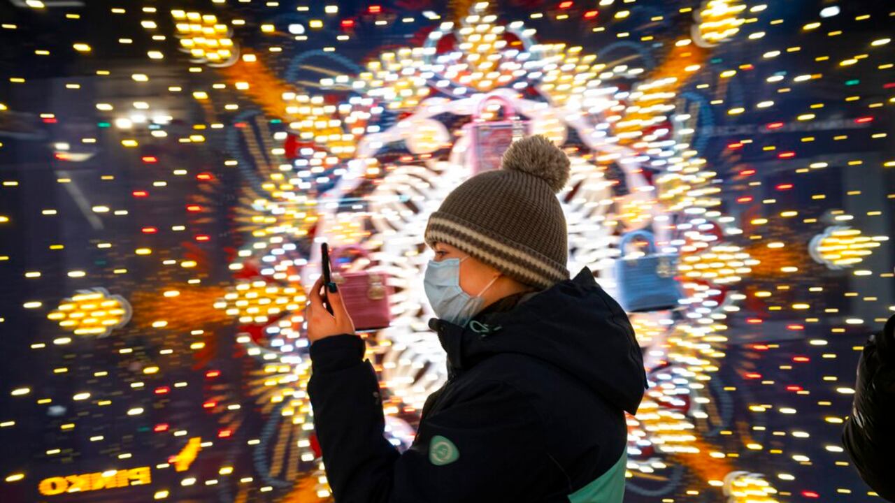 A visiter wearing a face mask to help curb the spread of the coronavirus looks at her smartphone as she walks in the GUM State Department store decorated for Christmas and New Year celebrations virtually empty due to the coronavirus pandemic in Moscow, Russia, Thursday, Dec. 3, 2020. Russia's coronavirus vaccine Sputnik V will be available for people in high-risk groups at 70 medical facilities in Moscow starting on Saturday. According to Moscow Mayor Sergei Sobyanin, those working in education and medical facilities, along with municipal workers, can get the shots. (AP Photo/Alexander Zemlianichenko)
