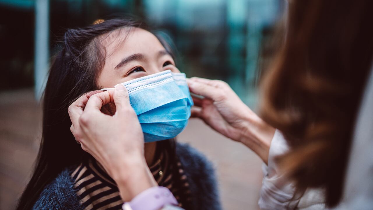 Mamá ayudando a su hija a usar mascarilla médica