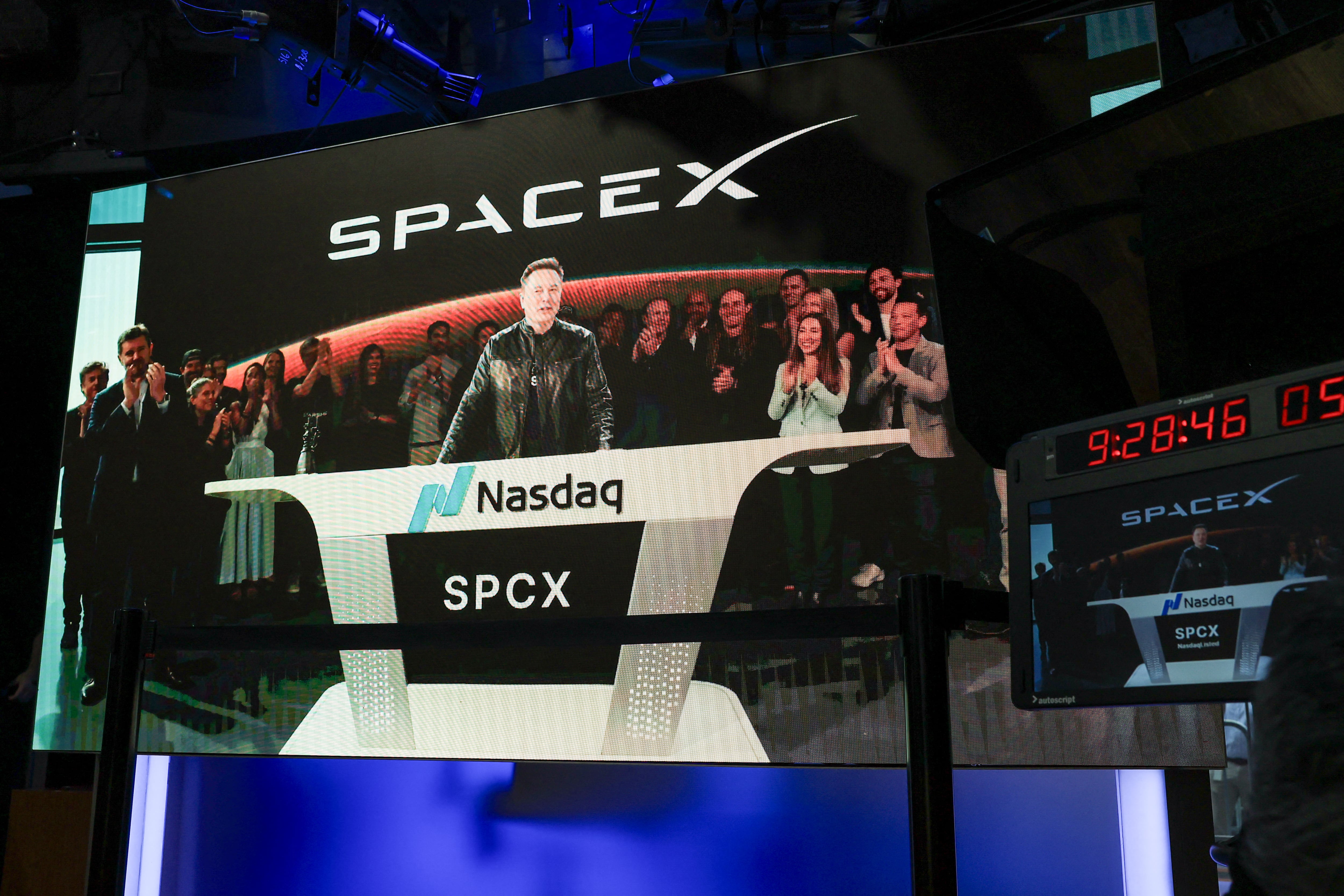 SpaceX CEO Elon Musk, displayed on a screen remotely from SpaceX headquarters in Starbase, Texas, speaks before the launch of SpaceX�s initial public offering (IPO) at the Nasdaq MarketSite in New York on June 12, 2026. Elon Musk's SpaceX begins trading on the Nasdaq exchange on Friday with the biggest initial public offering in history expected to make the polarizing entrepreneur the world's first trillionaire. The company priced more than 555 million shares at $135 each in a filing with the US markets regulator on Thursday, placing SpaceX in the top 10 of Wall Street's biggest companies with a valuation of just under $1.8 trillion -- ahead of Tesla, Facebook-owner Meta and Walmart. (Photo by TIMOTHY A. CLARY / AFP)