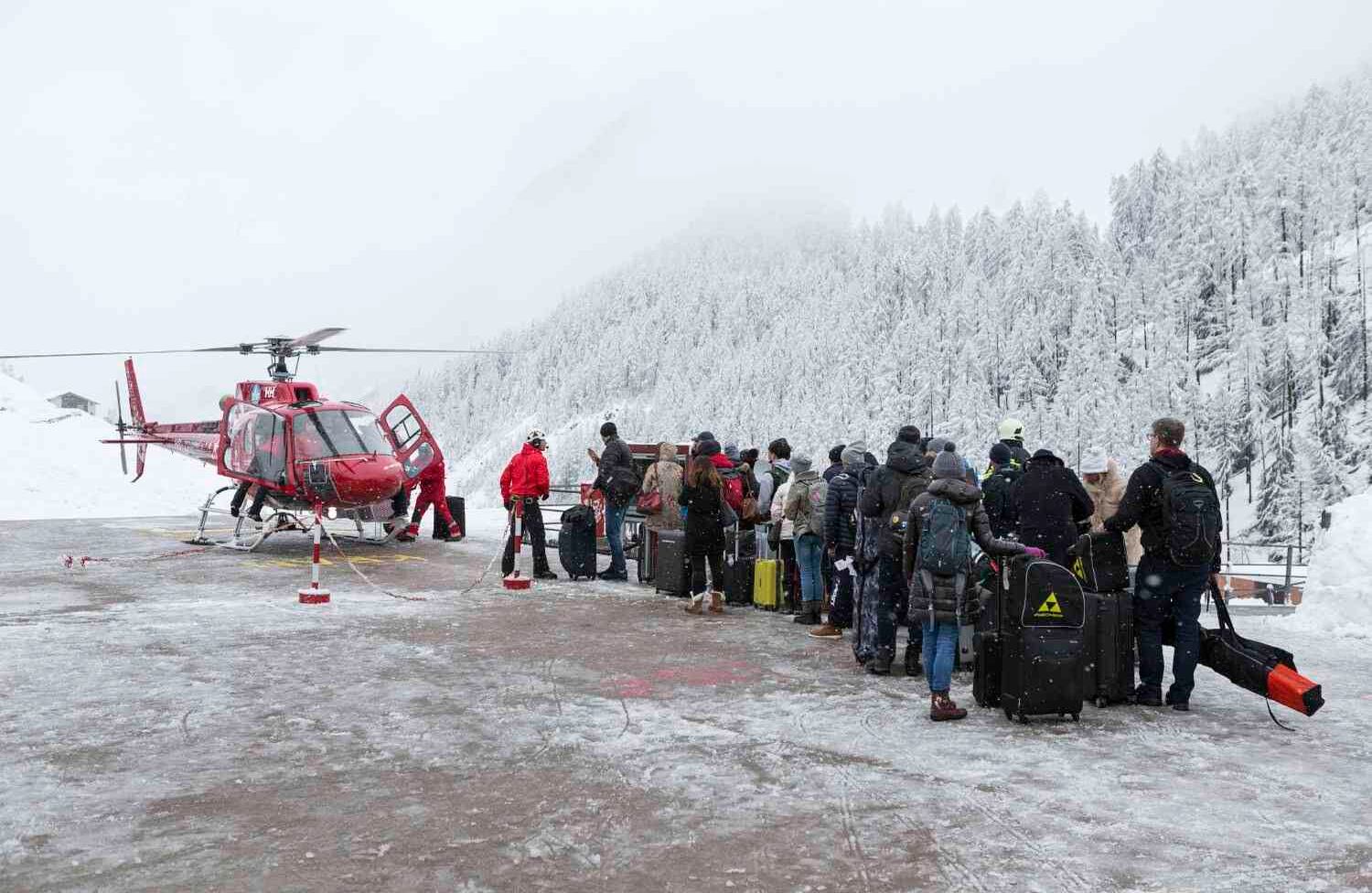 Los turistas esperan en fila en el helipuerto de Air Zermatt para tomar un vuelo por puente aéreo al valle hasta Raron, en Zermatt, el martes 9 de enero de 2018. Debido a fuertes nevadas y lluvias, a Zermatt solo se puede llegar por aire. (Dominic Steinmann / Keystone vía AP).