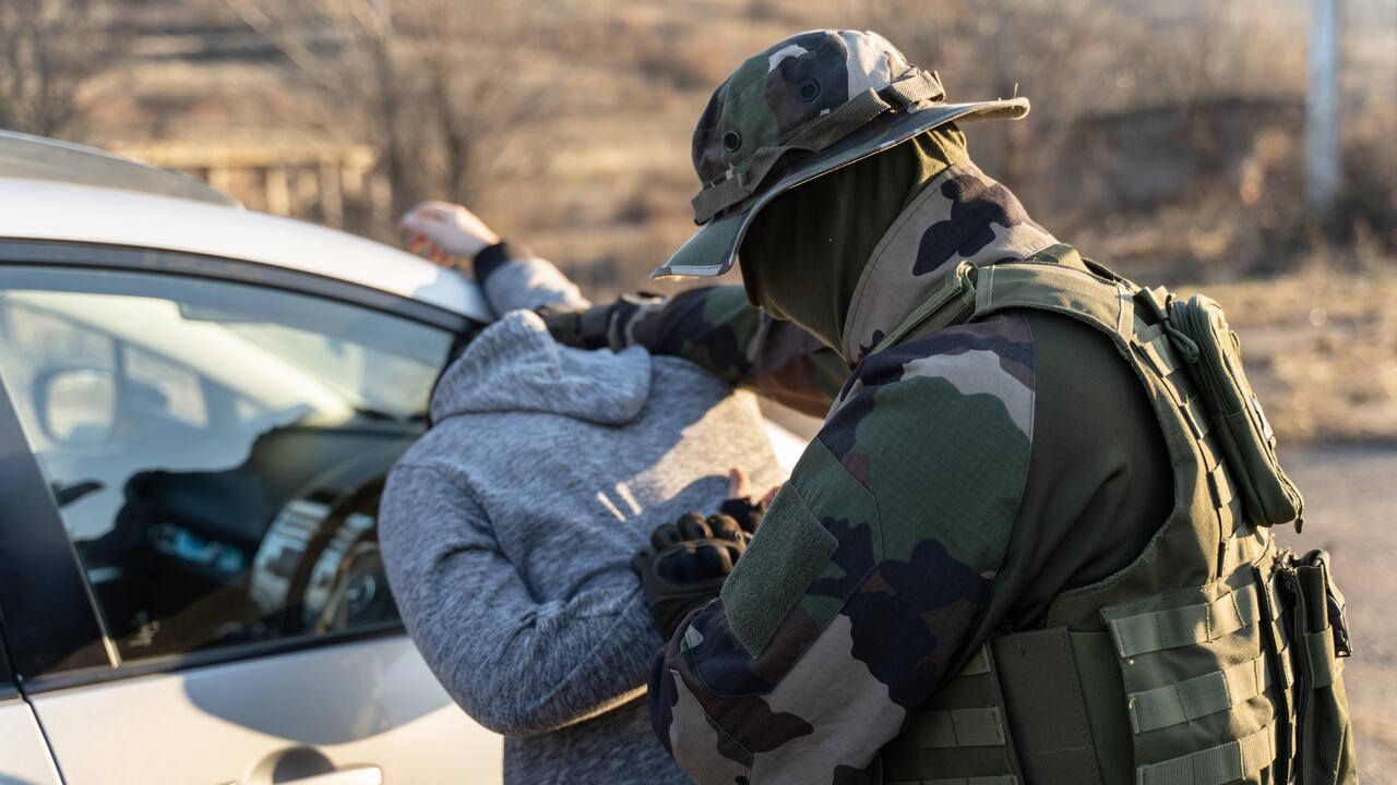 Vista trasera de un hombre militar desconocido arrestando a un migrante