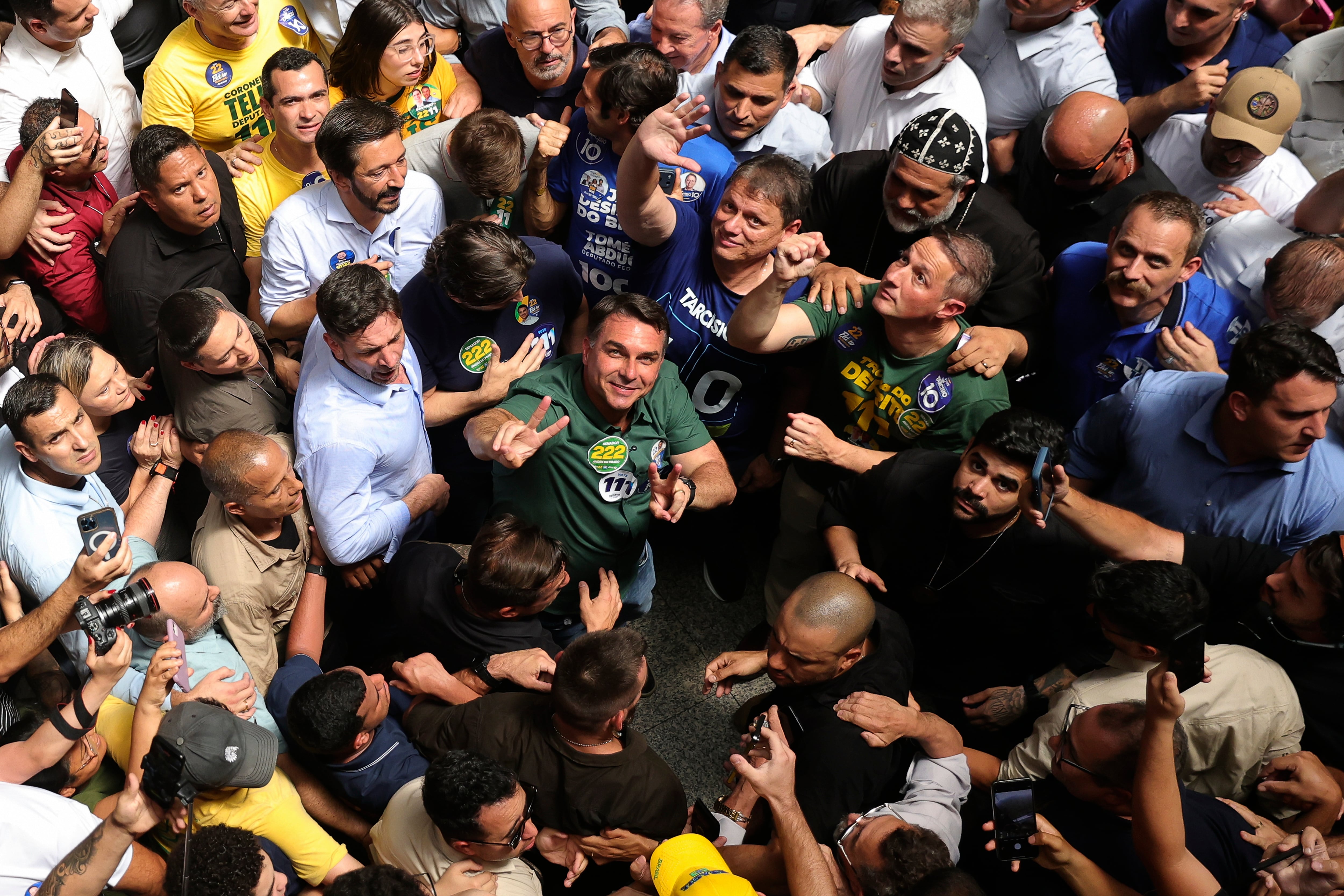 El aspirante a la presidencia de Brasil, el senador Flávio Bolsonaro (centro), vestido de verde y mirando hacia arriba, hace campaña en Sao Paulo, Brasil.
