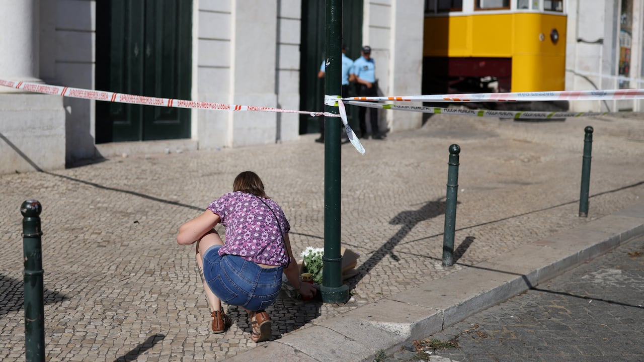 Una mujer deposita flores en homenaje a las víctimas en el lugar del Funicular Gloria, el día después del accidente que dejó 16 muertos en Lisboa, el 4 de septiembre de 2025.